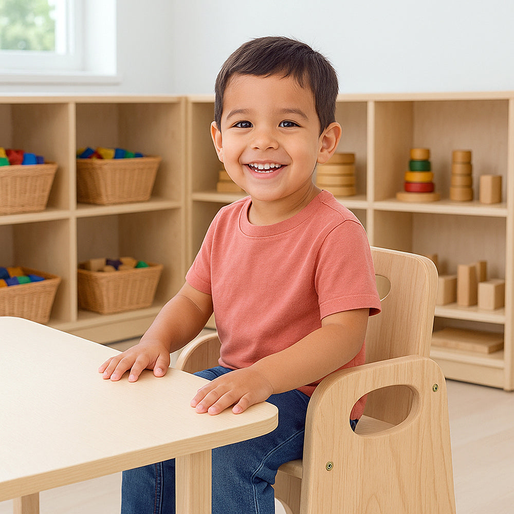 Child sitting at a table in a classroom setting with educational materials in the background