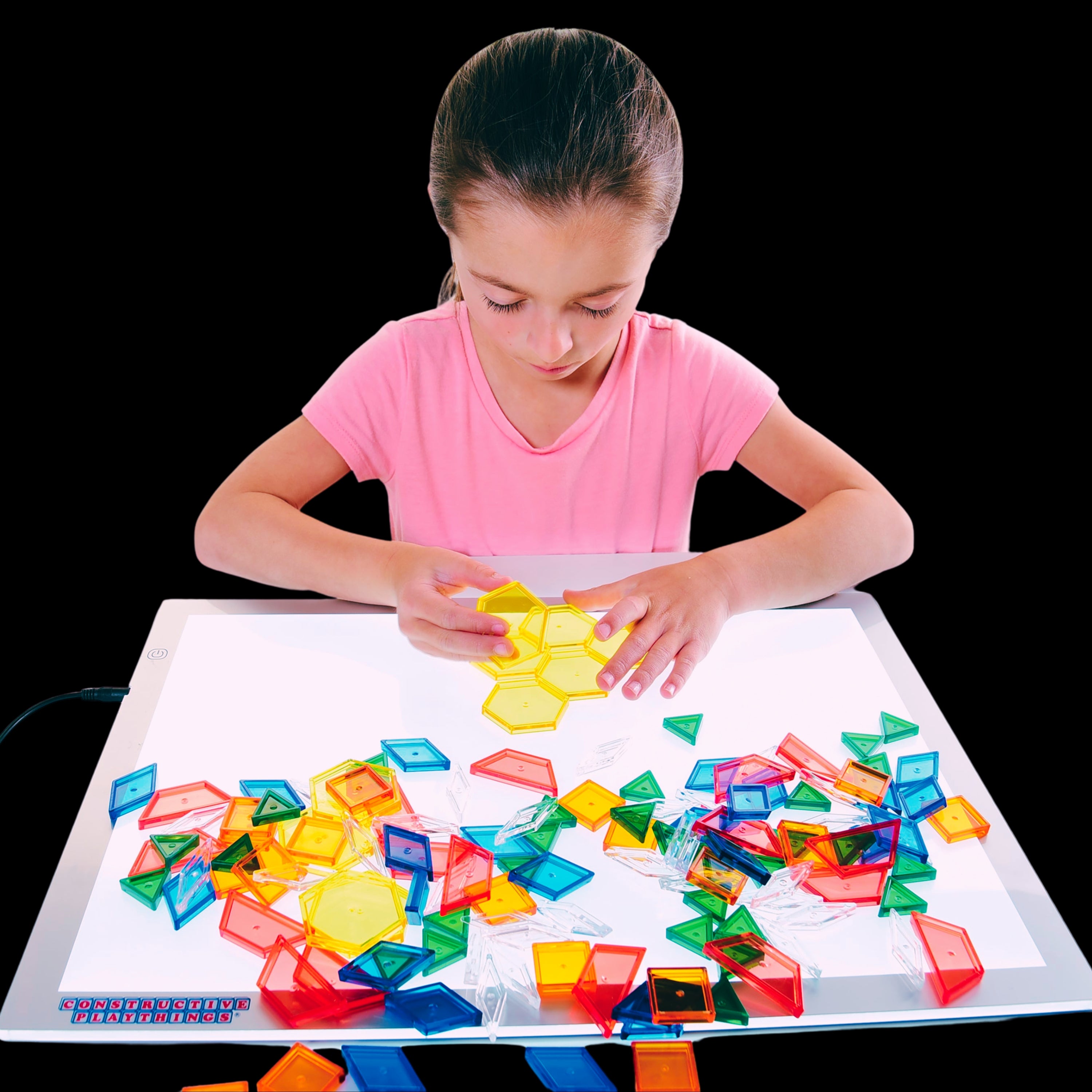 Kid using translucent pattern blocks on light panel