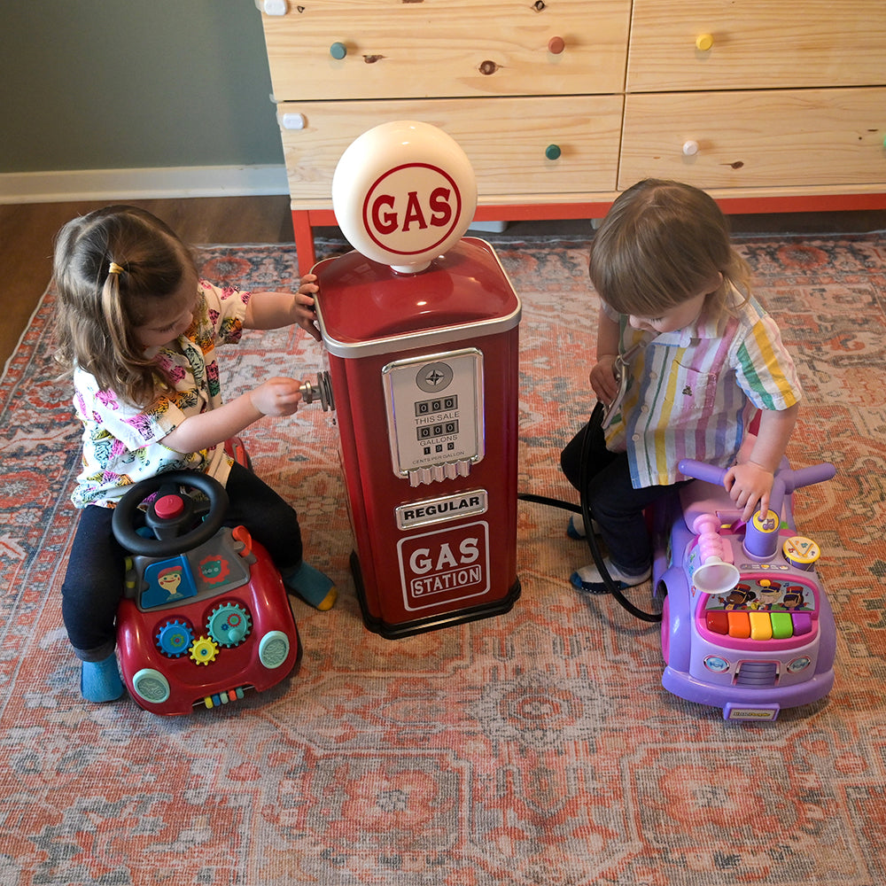 Two Toddlers Interacting with Steel Gas Pump Replica