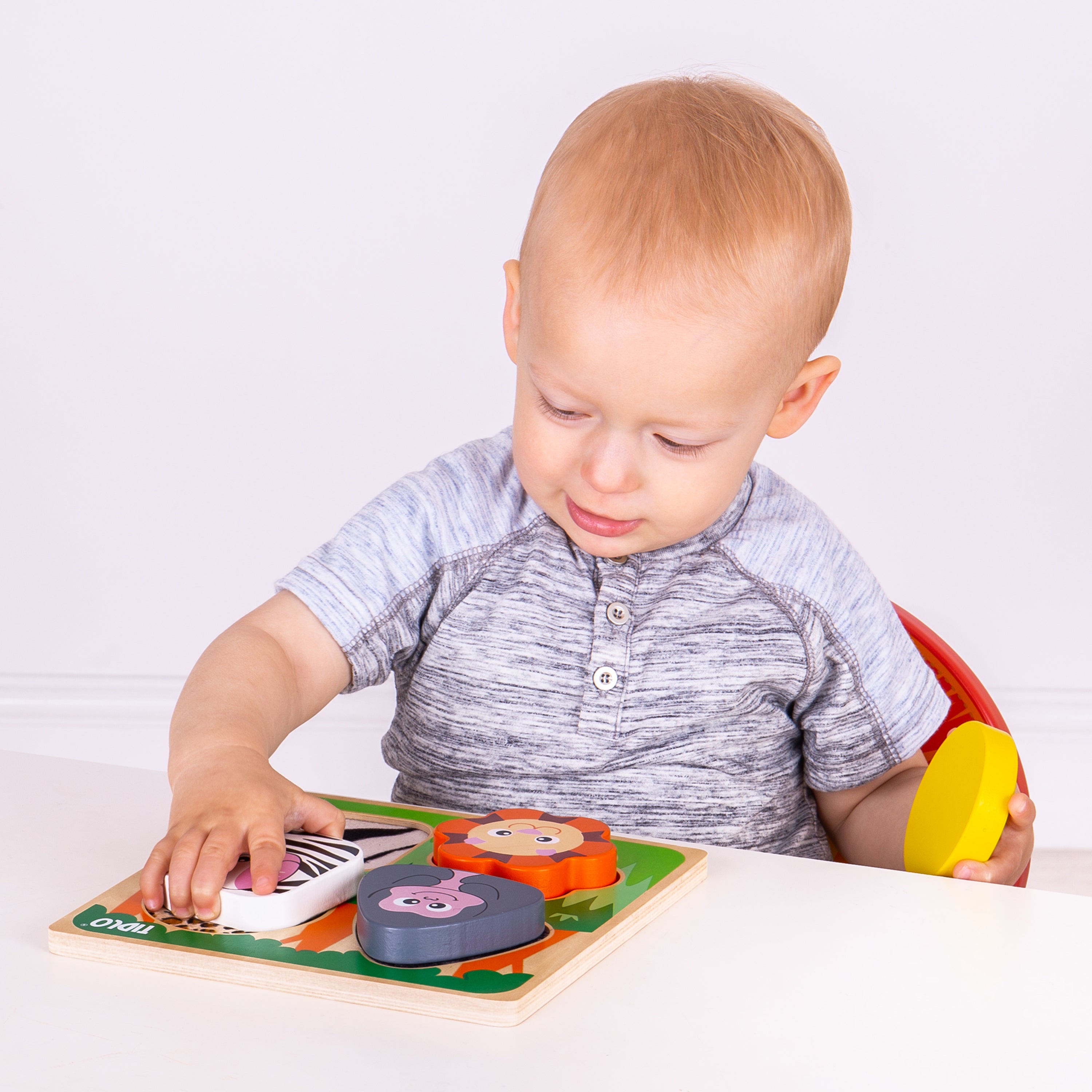 Child playing with a wooden puzzle toy on a white background