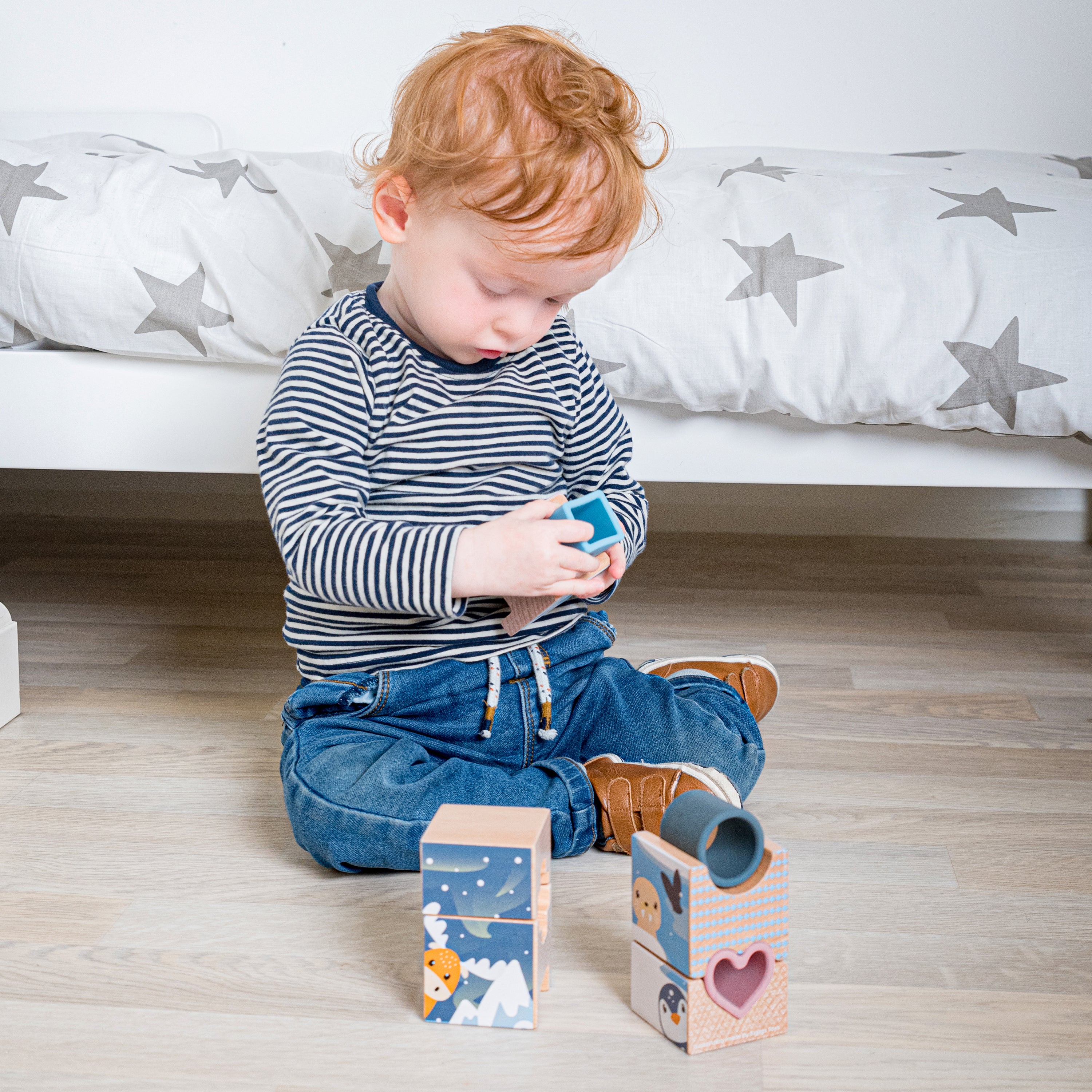 Child playing with wooden blocks on a wooden floor.