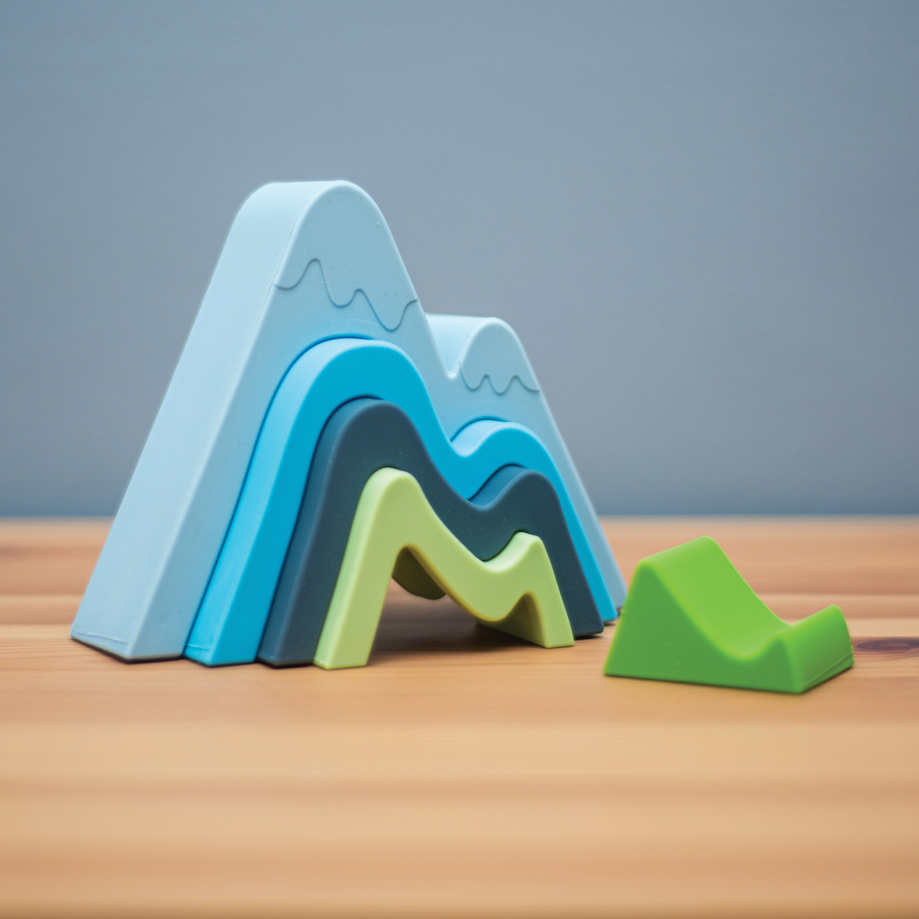 Stack of colorful foam blocks on a wooden surface with a gray background