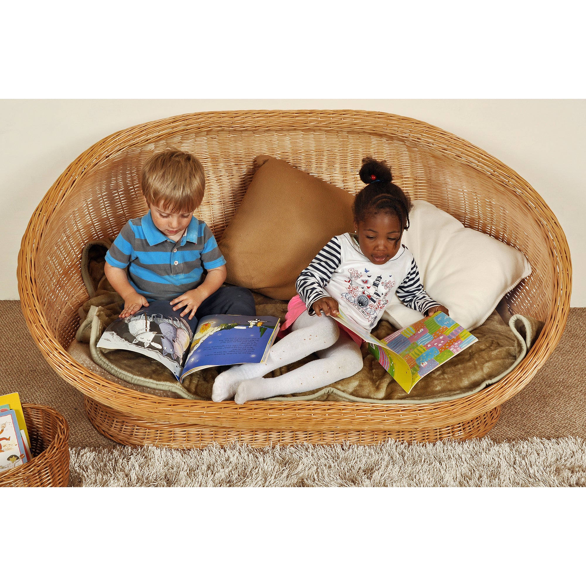 Two children sitting in a wicker couch reading books.