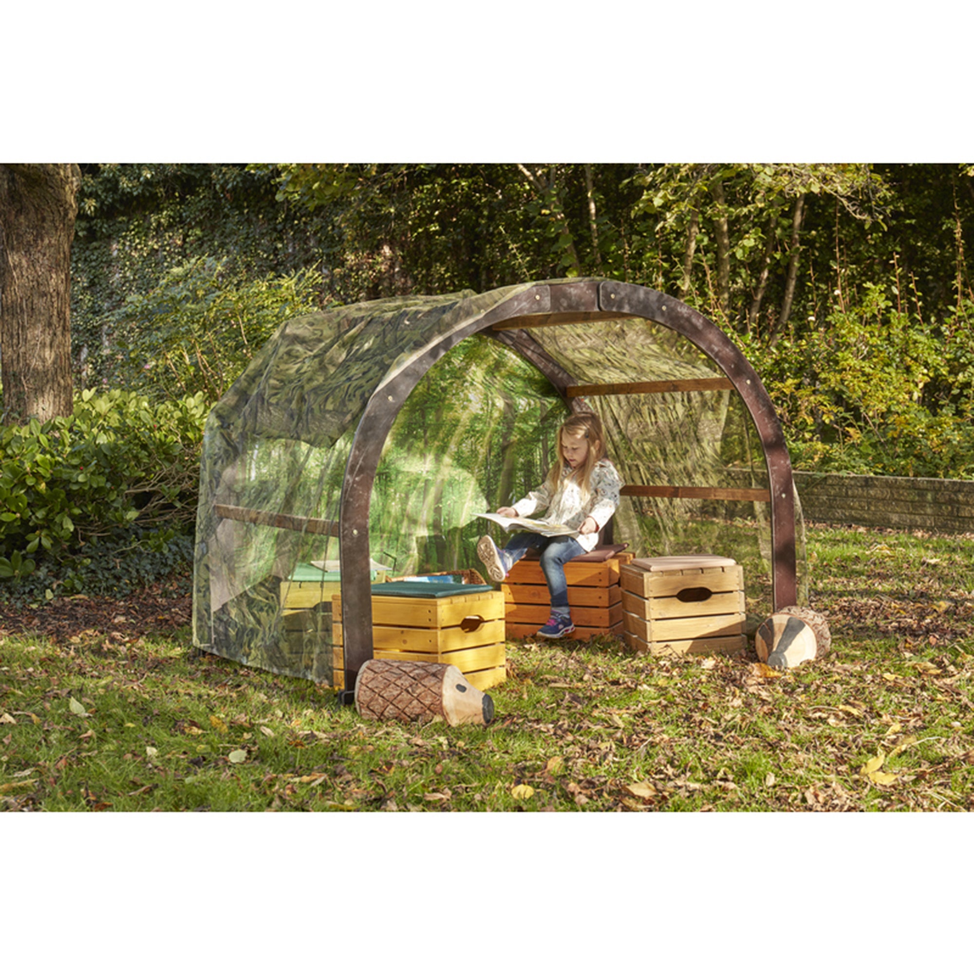Child sitting under a transparent canopy structure in a natural setting