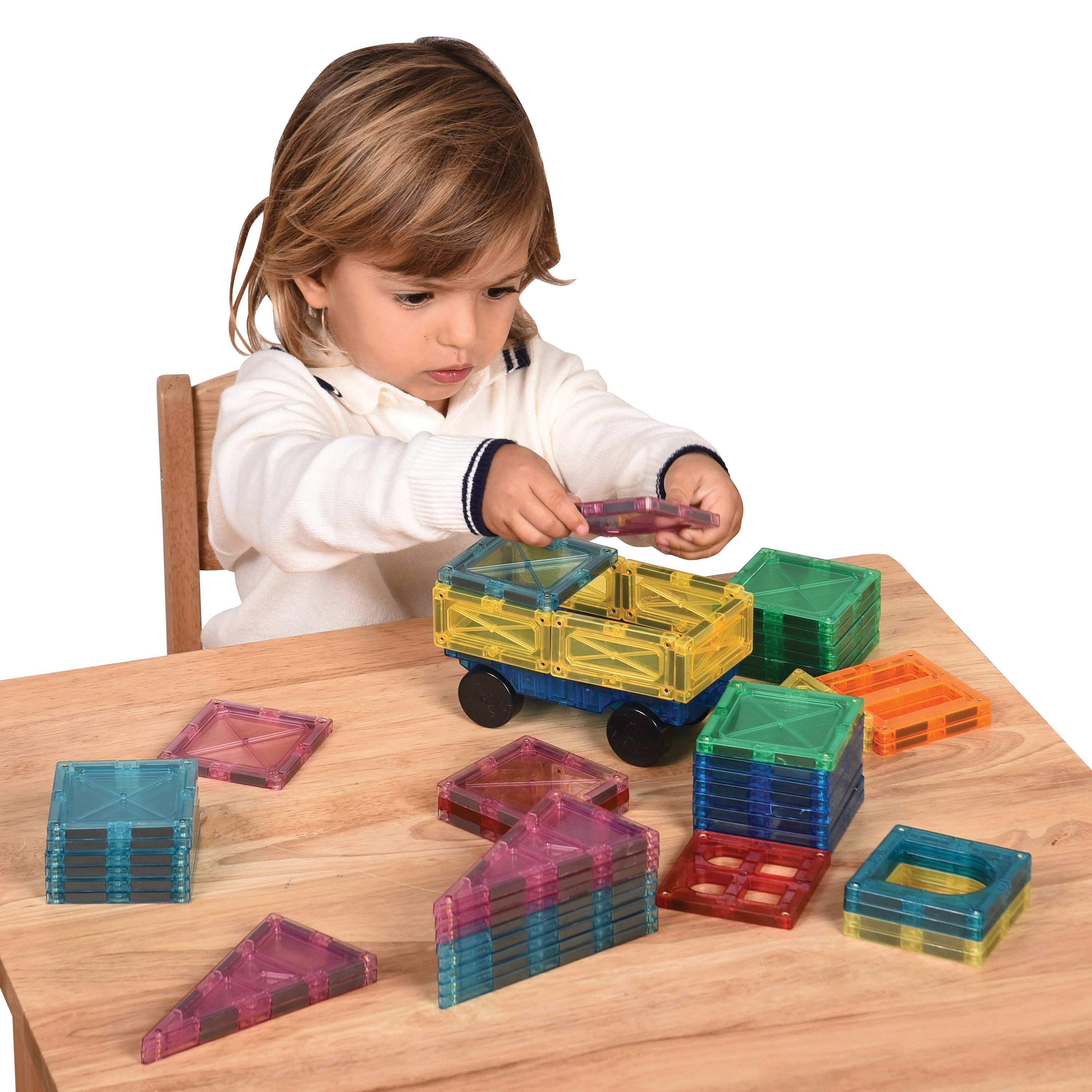 Child playing with colorful transparent building blocks on a wooden table.