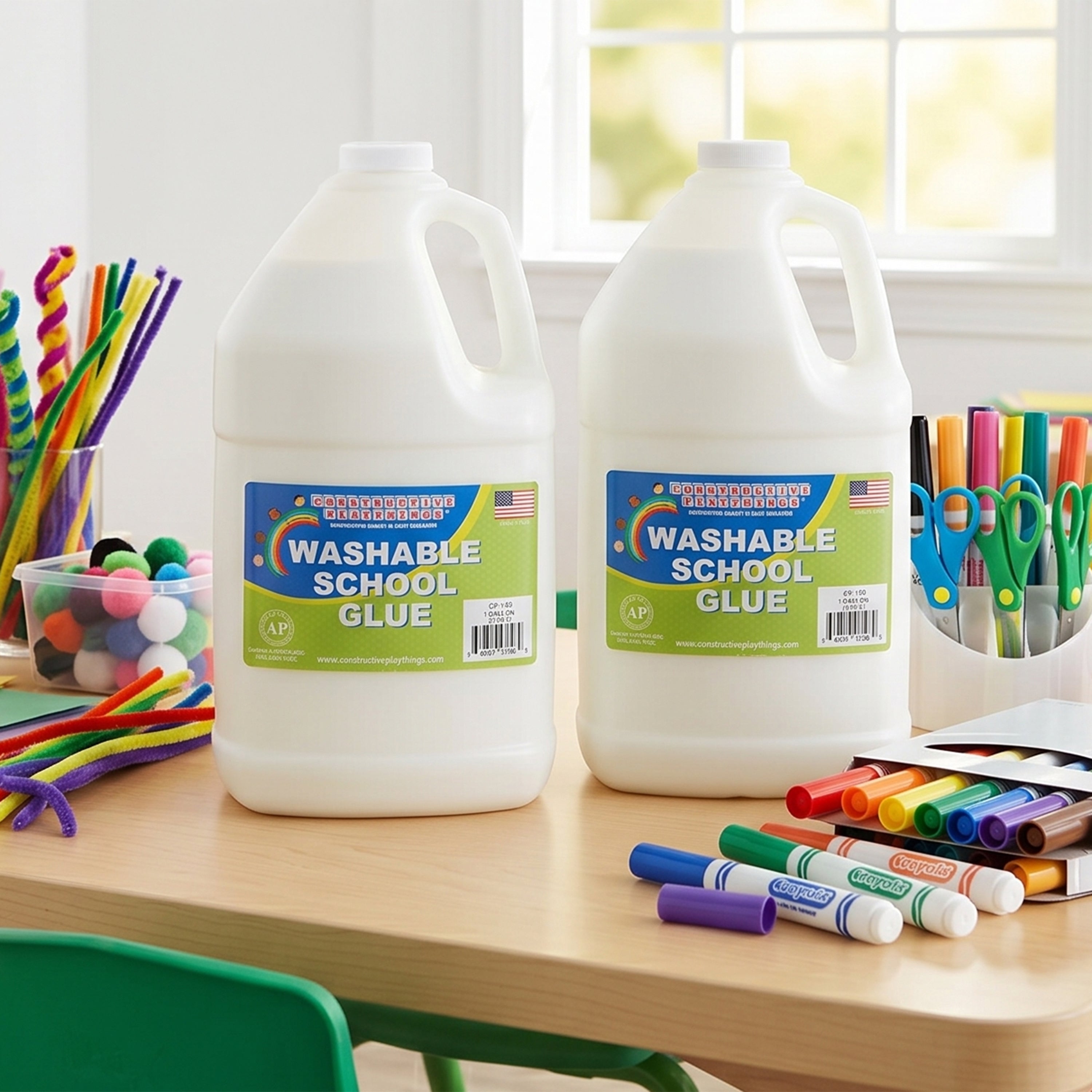 Two large bottles of washable school glue on a table with markers and other supplies.