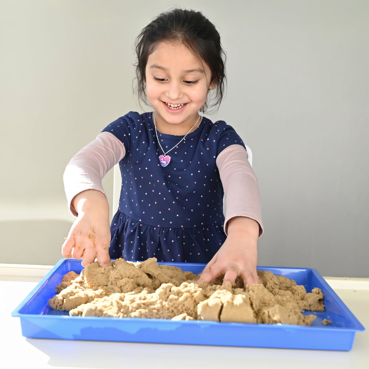 Child playing with Wonder Flow Sensory Sand in a sensory tray for creative fine motor play