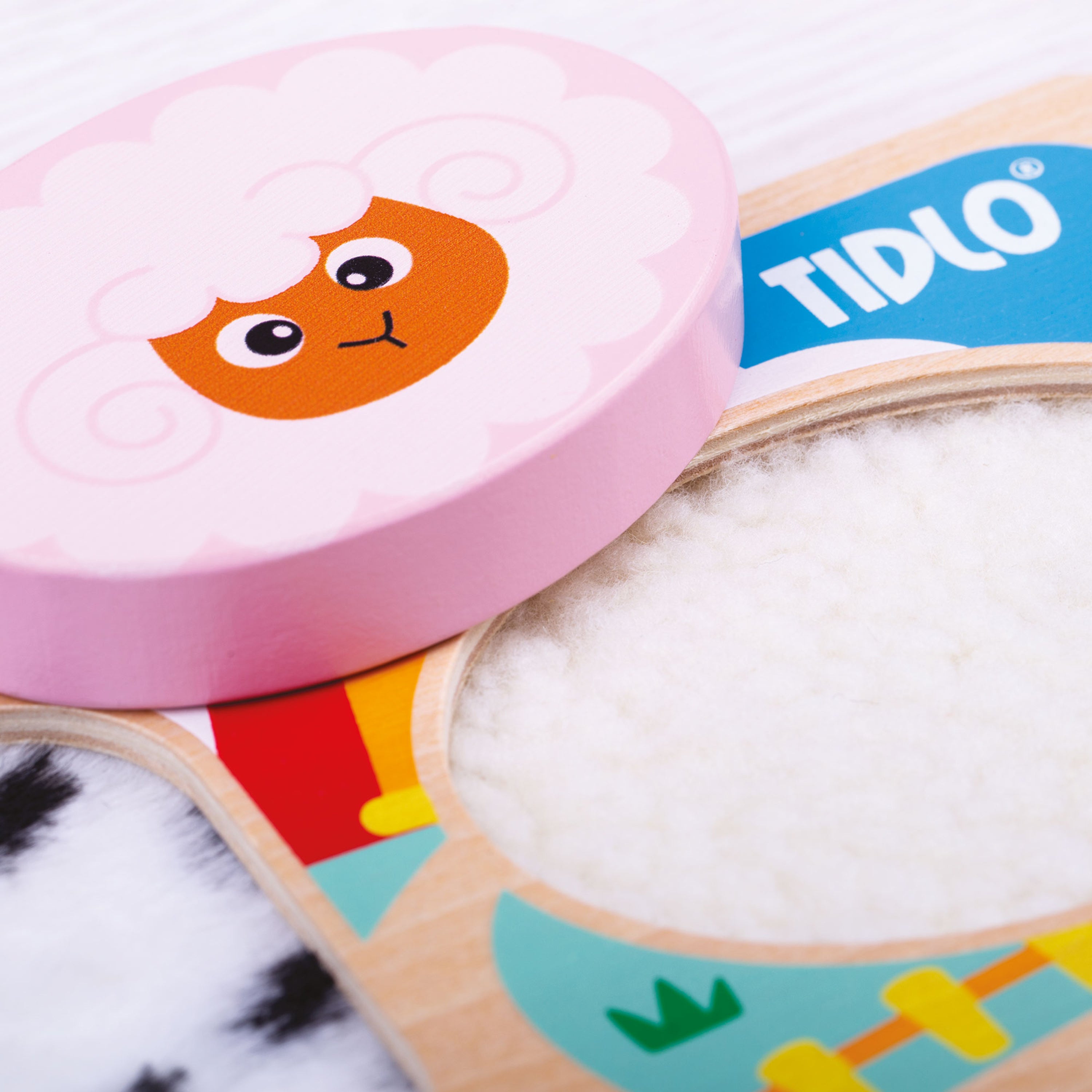 TIDLO toy with pink puzzle piece featuring a cartoon character, open to reveal white stuffing inside.