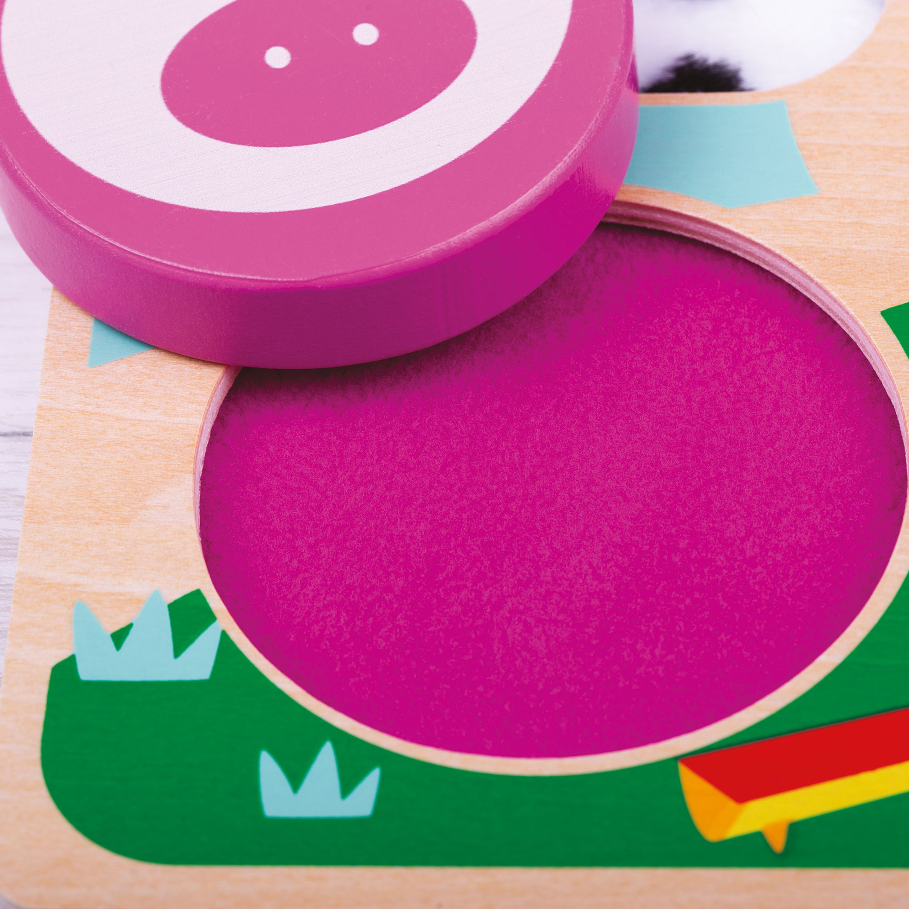 Colorful wooden toy with a pink circular piece on a white background
