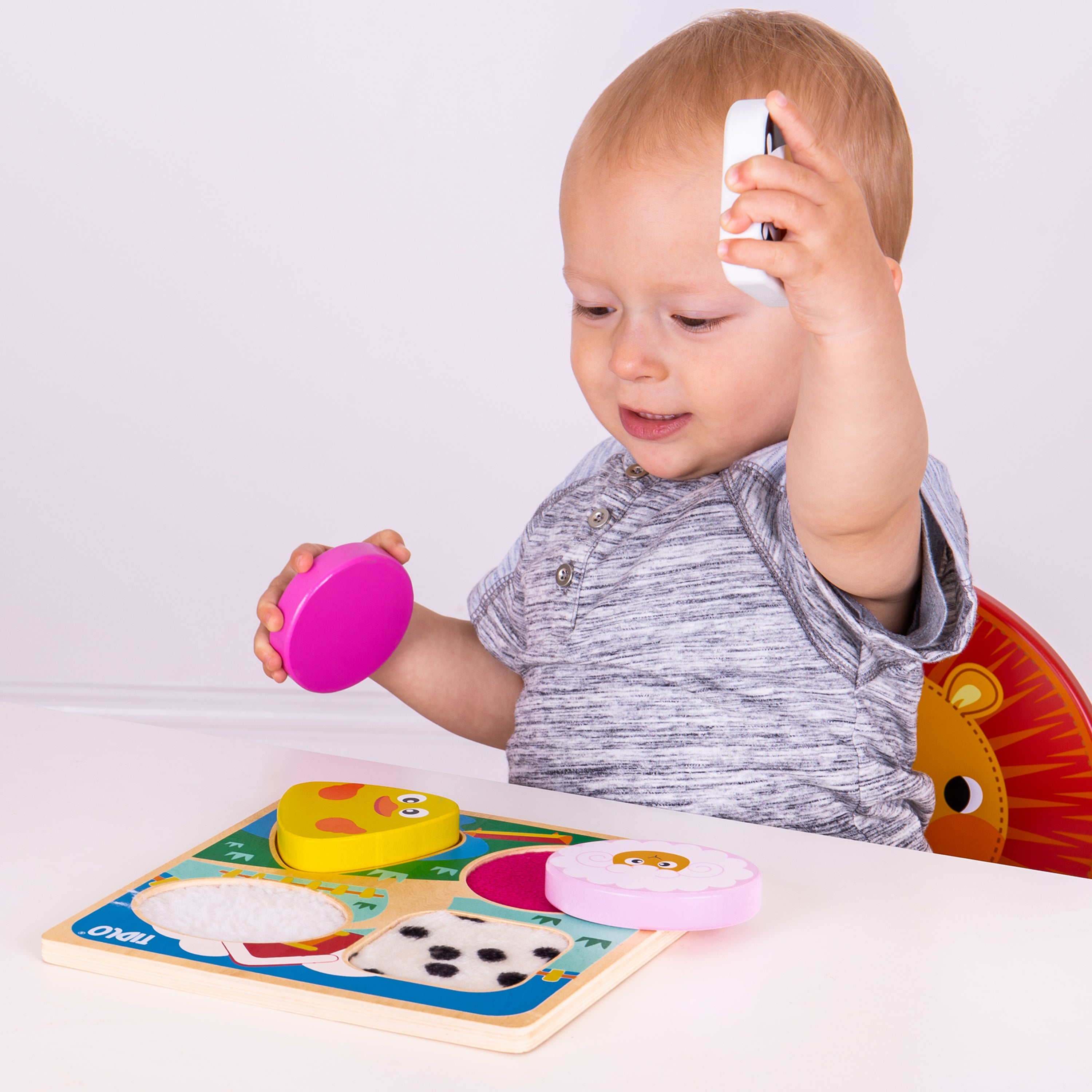 Child playing with a colorful puzzle on a white surface