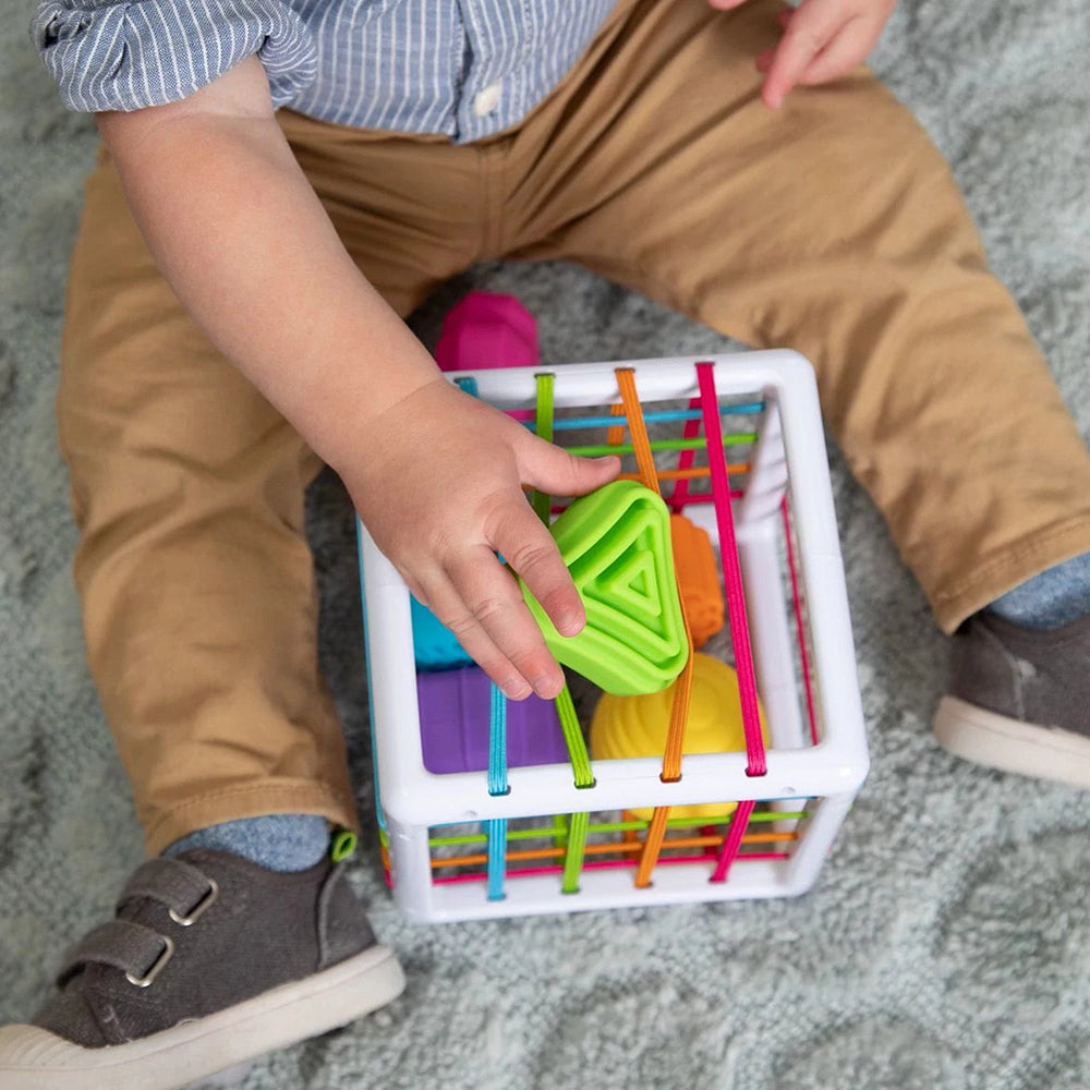 Toddler Pushing Green Shape Into Top of Sensory Shape-Sorting Cube