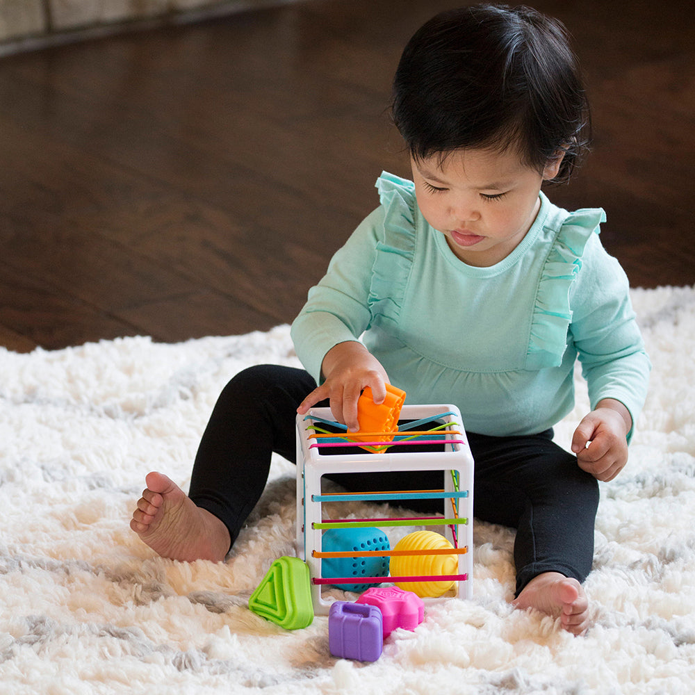 Toddler Pushing Orange Shape Into Top of Sensory Shape-Sorting Cube