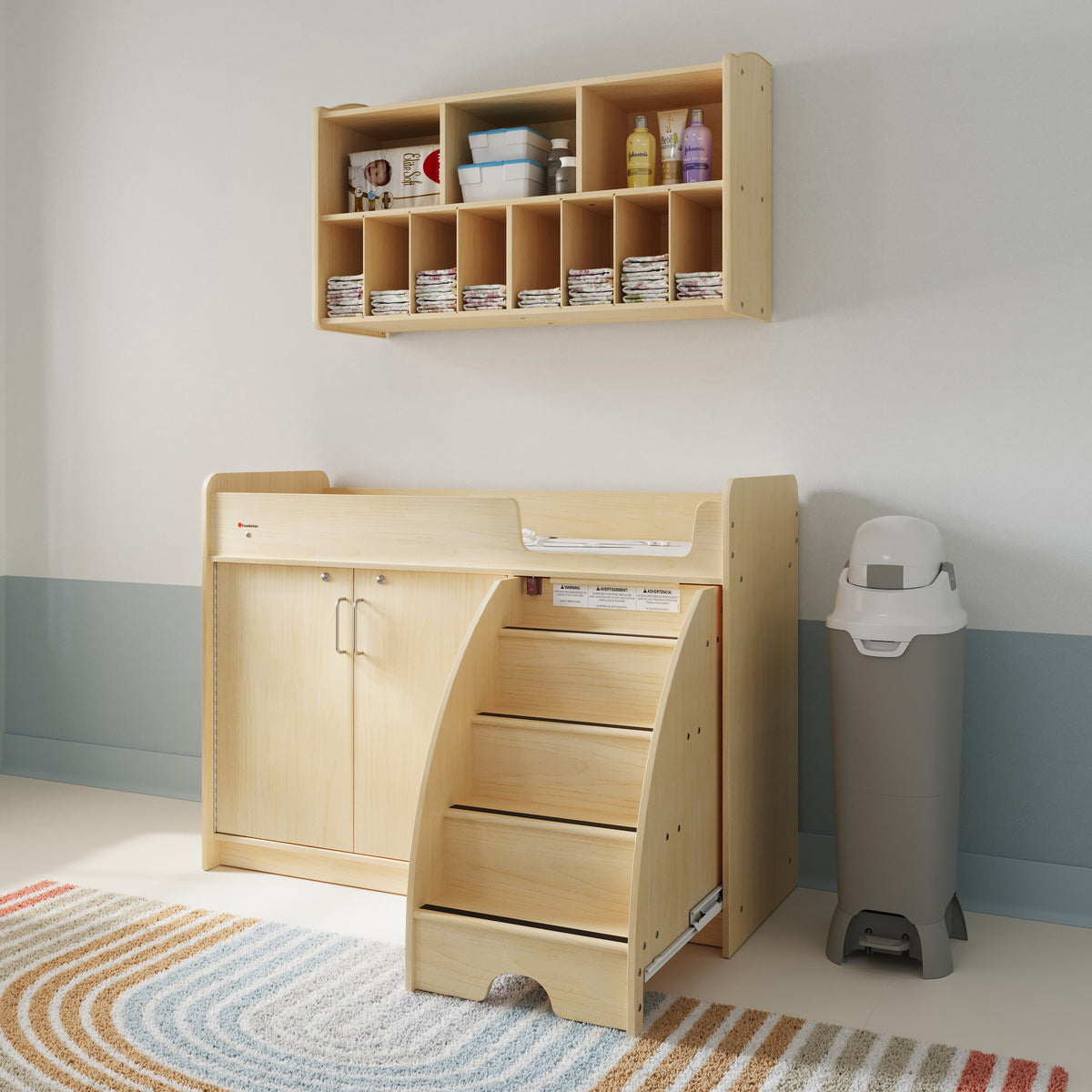 Premium tall diaper pail with foot pedal beside a childcare changing station and wall-mounted diaper organizer