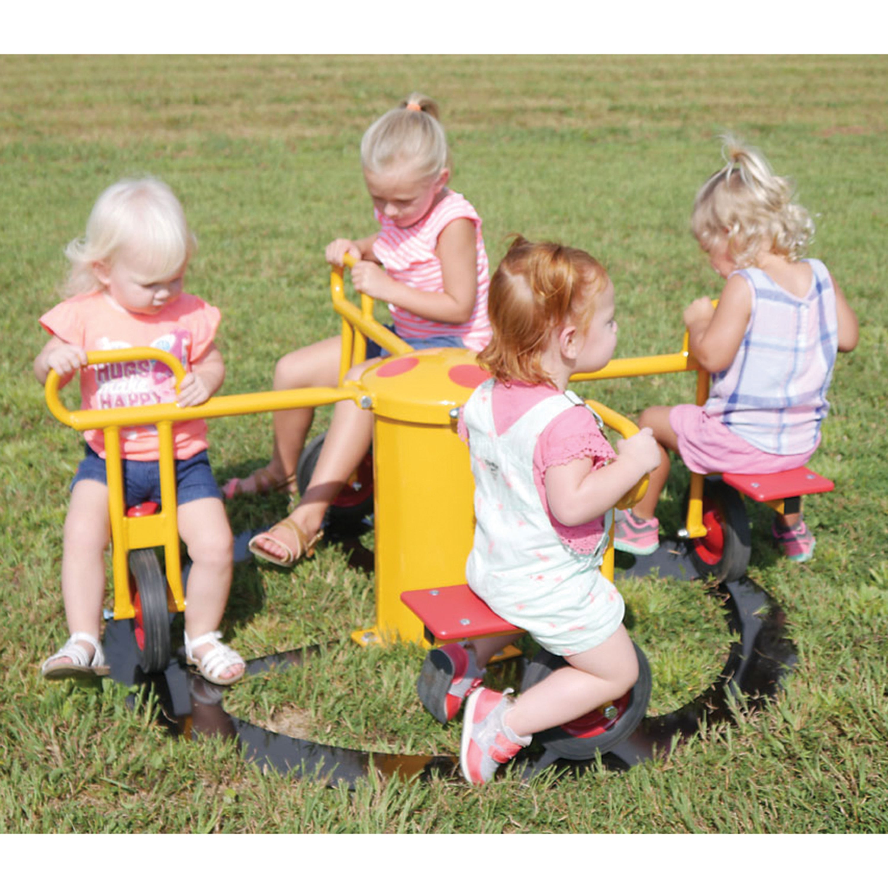Four children playing on trikes in a grassy area