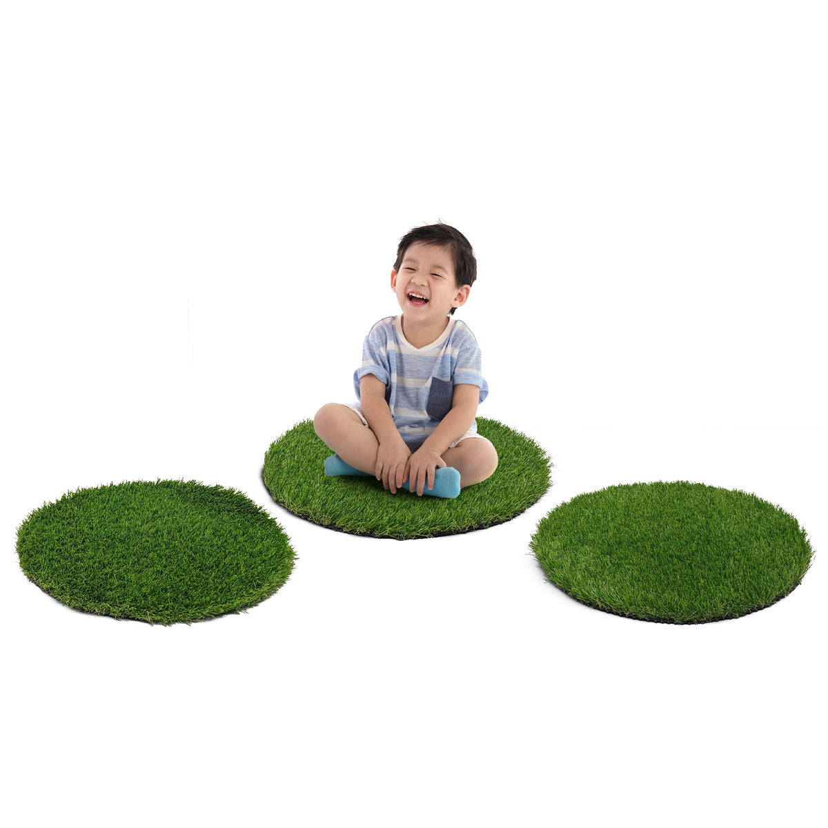 A child sitting on three round green artificial grass turf pads