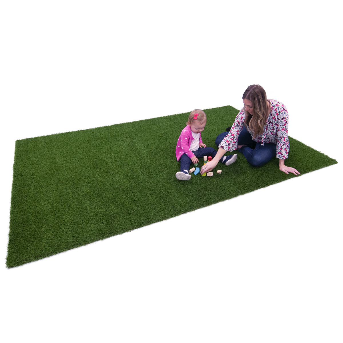 A rectangular green artificial turf mat shown on a white background, with a woman and a young child sitting on it and playing with small toy blocks.