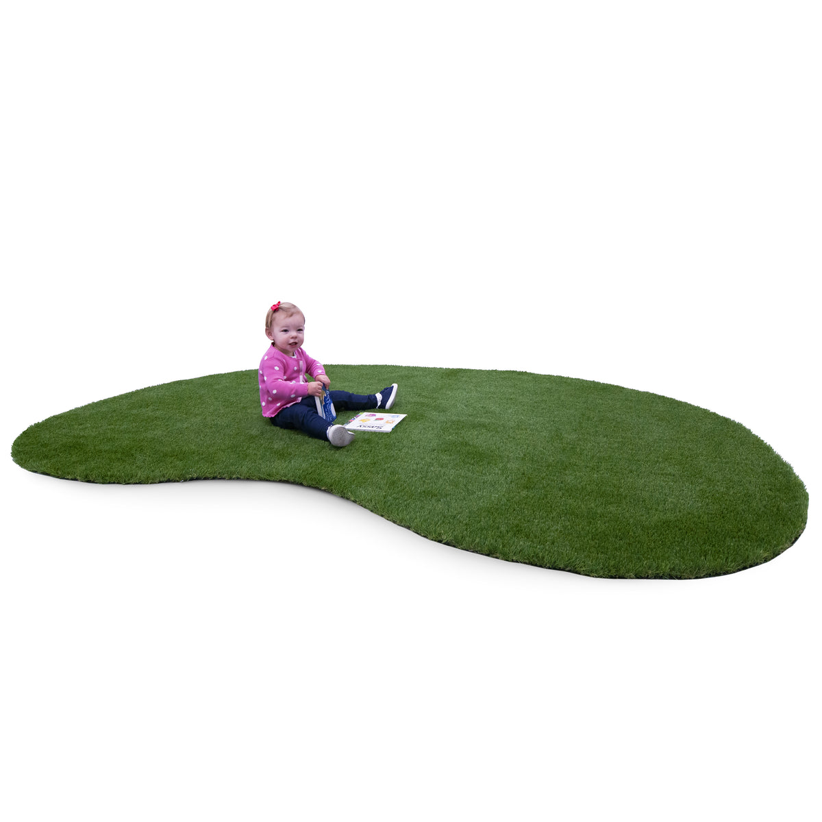 A toddler sits on a large, organic-shaped green artificial turf rug against a solid white background.