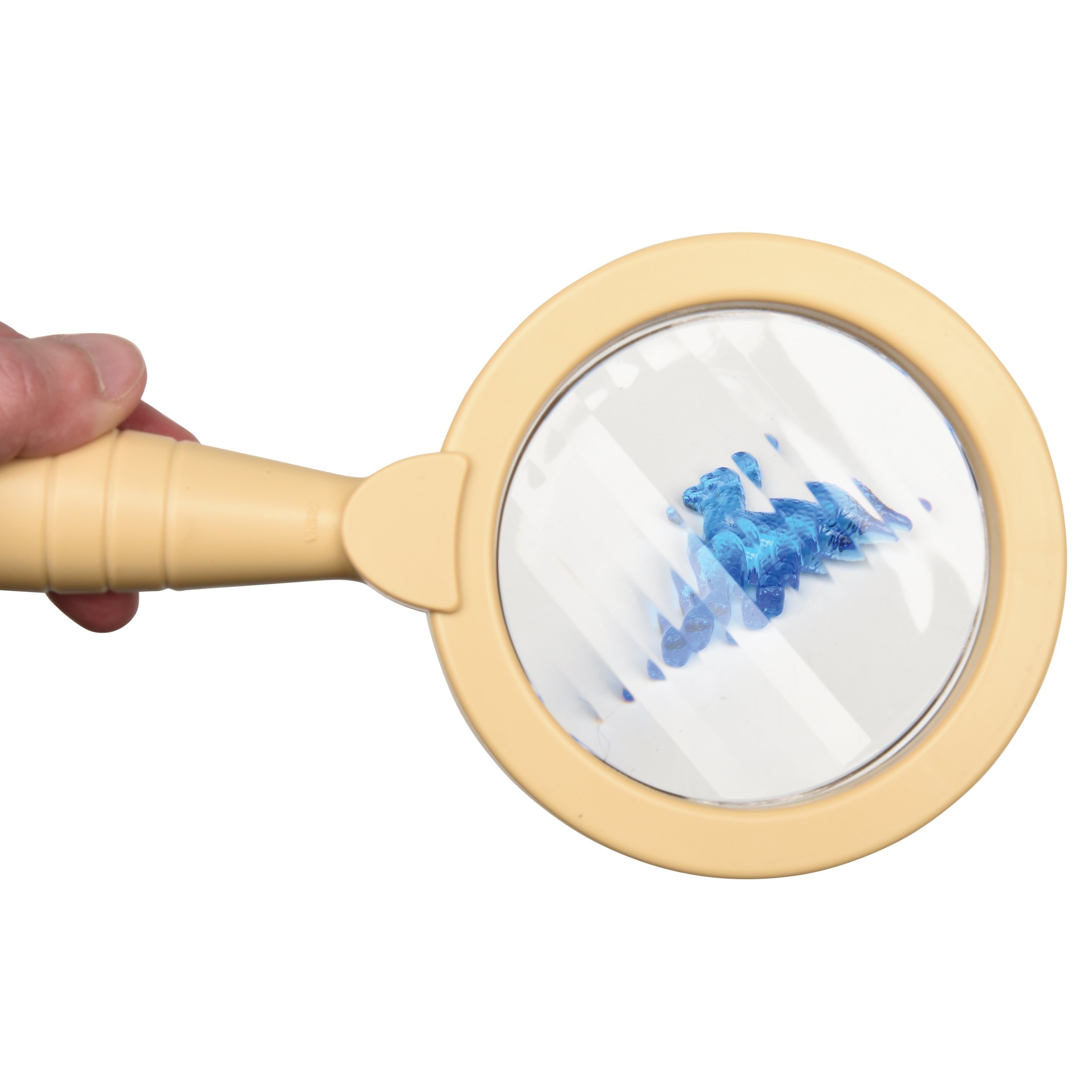 Beige magnifying glass held by a hand with a blue dinosaur toy visible through the lens on a white background