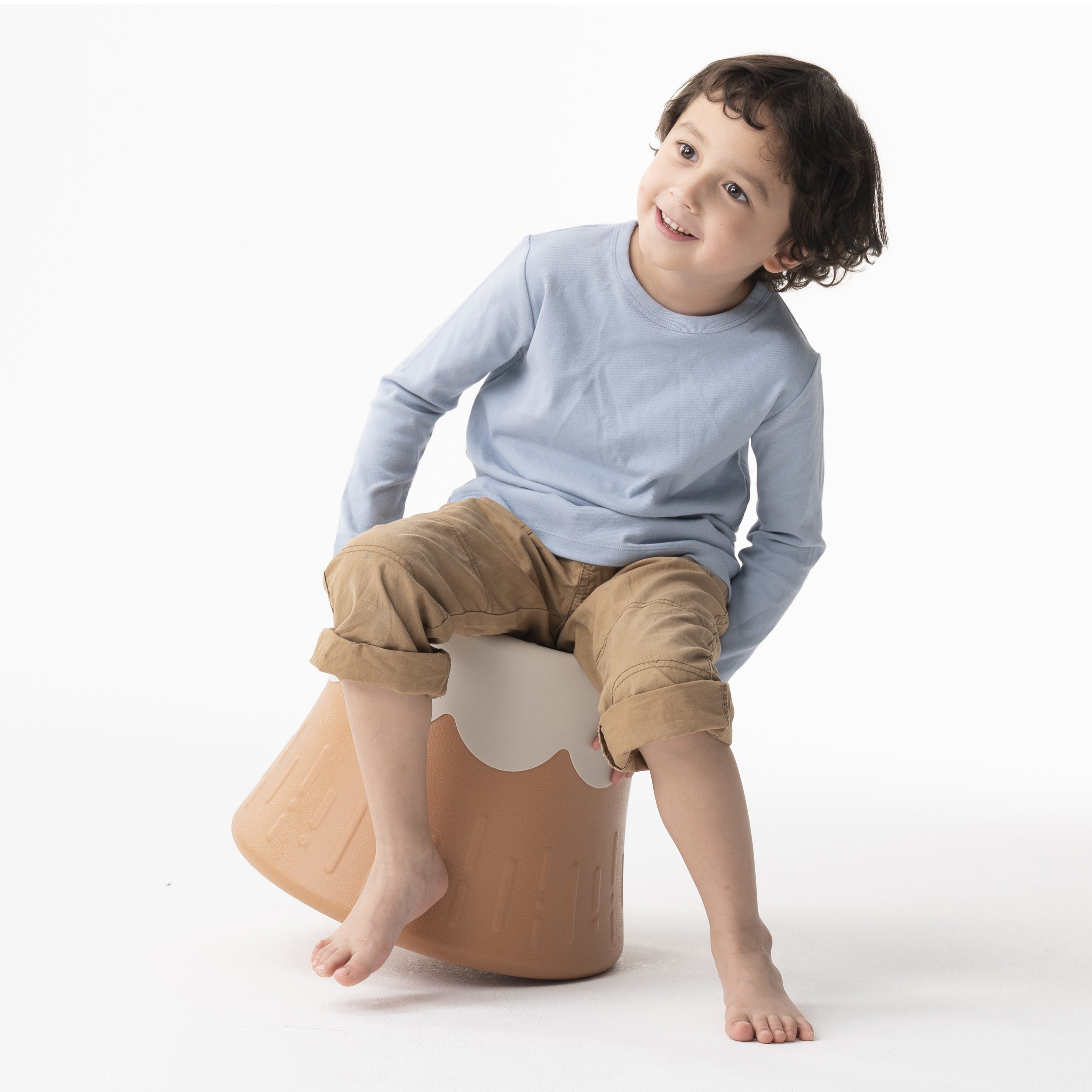 Child sitting on a brown stool with a white cloud design against a white background