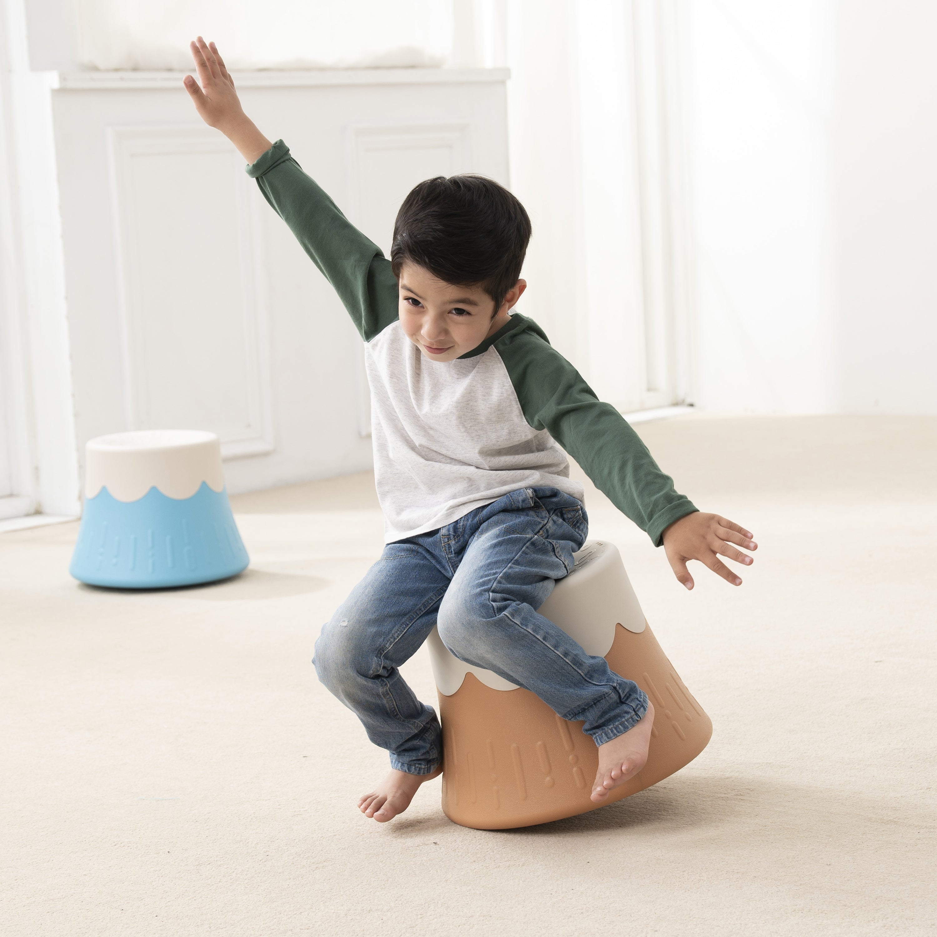 Child sitting on a volcano themed chair with a white background