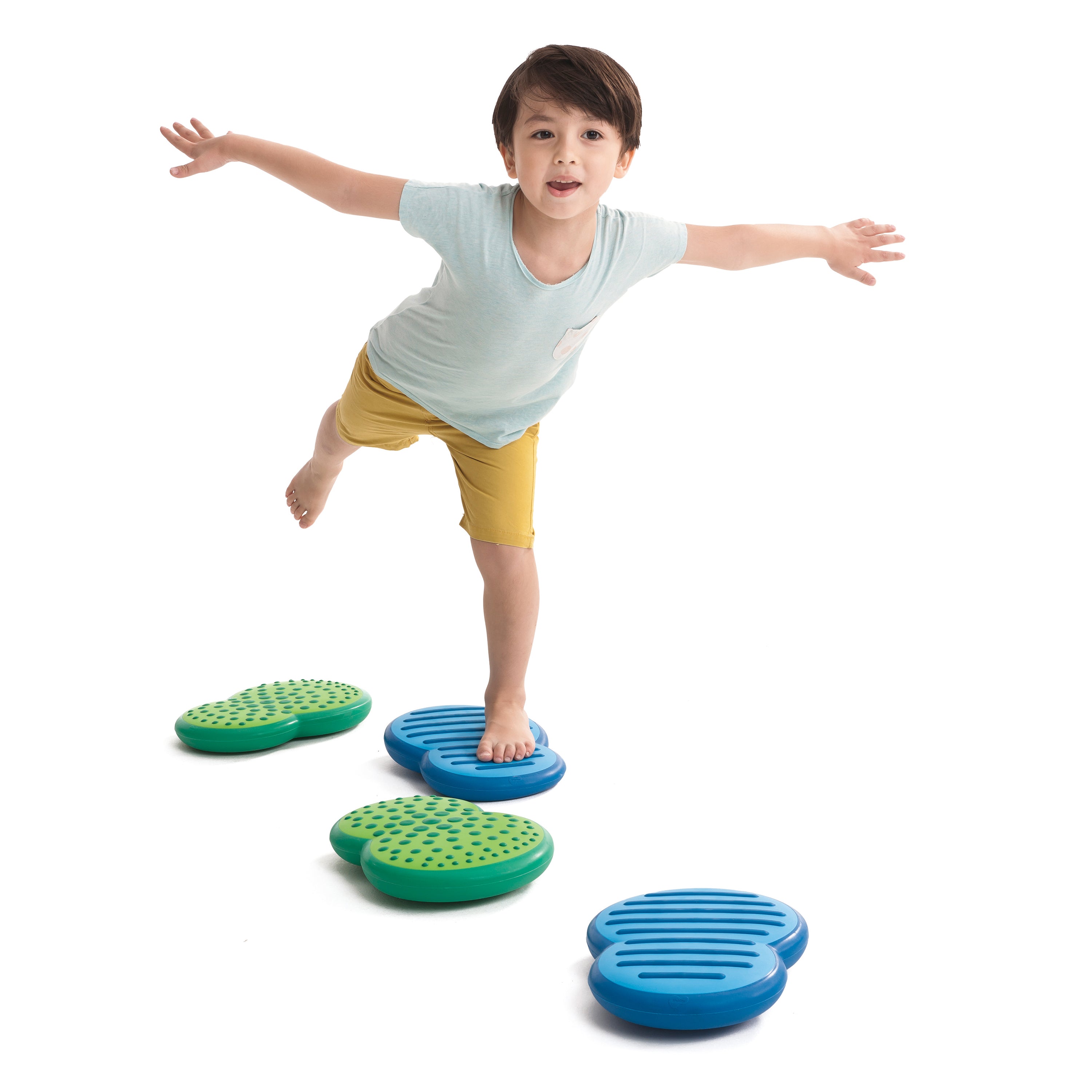 Child balancing on a set of blue and green balance steps against a white background