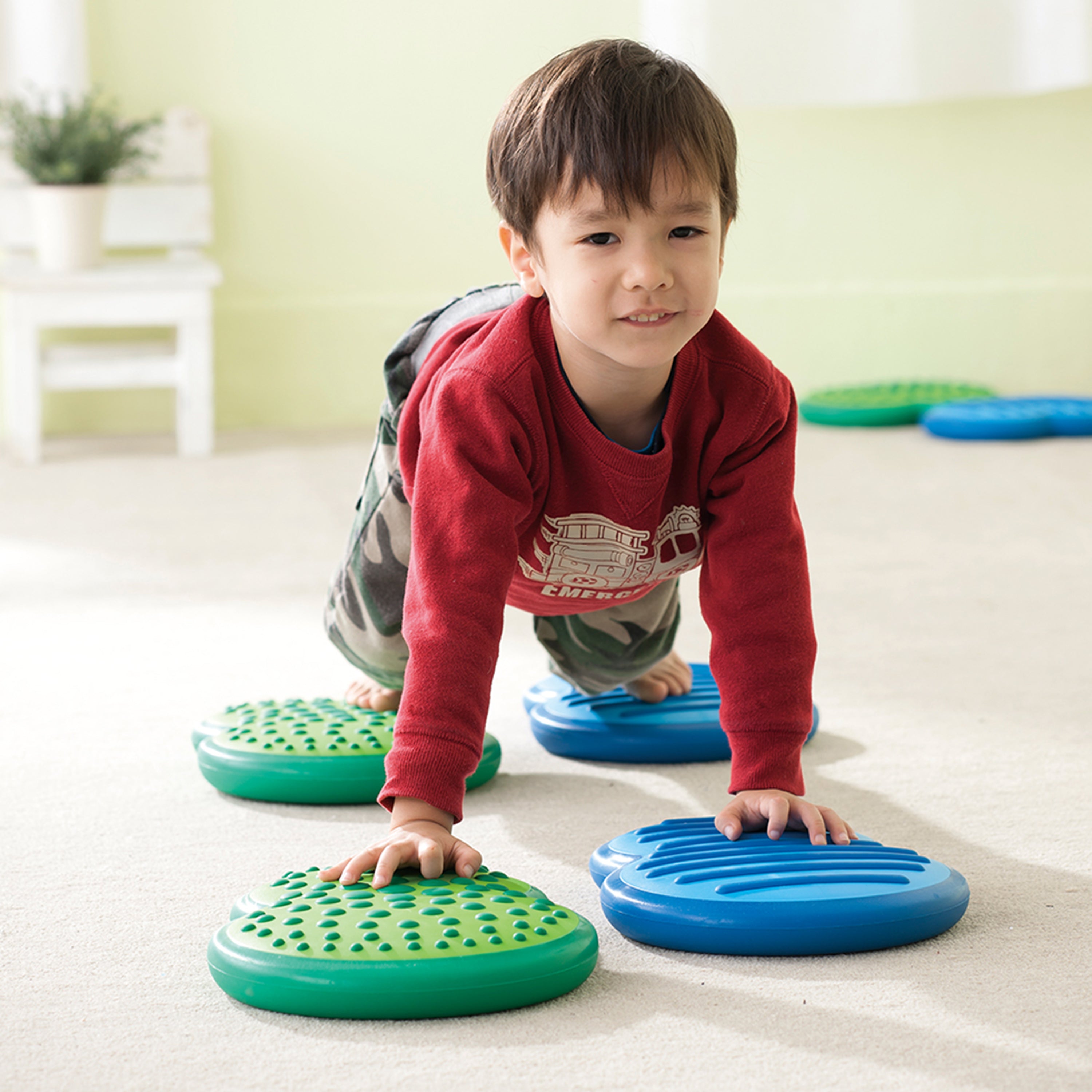 Child playing with colorful stepping stones on a light-colored floor.