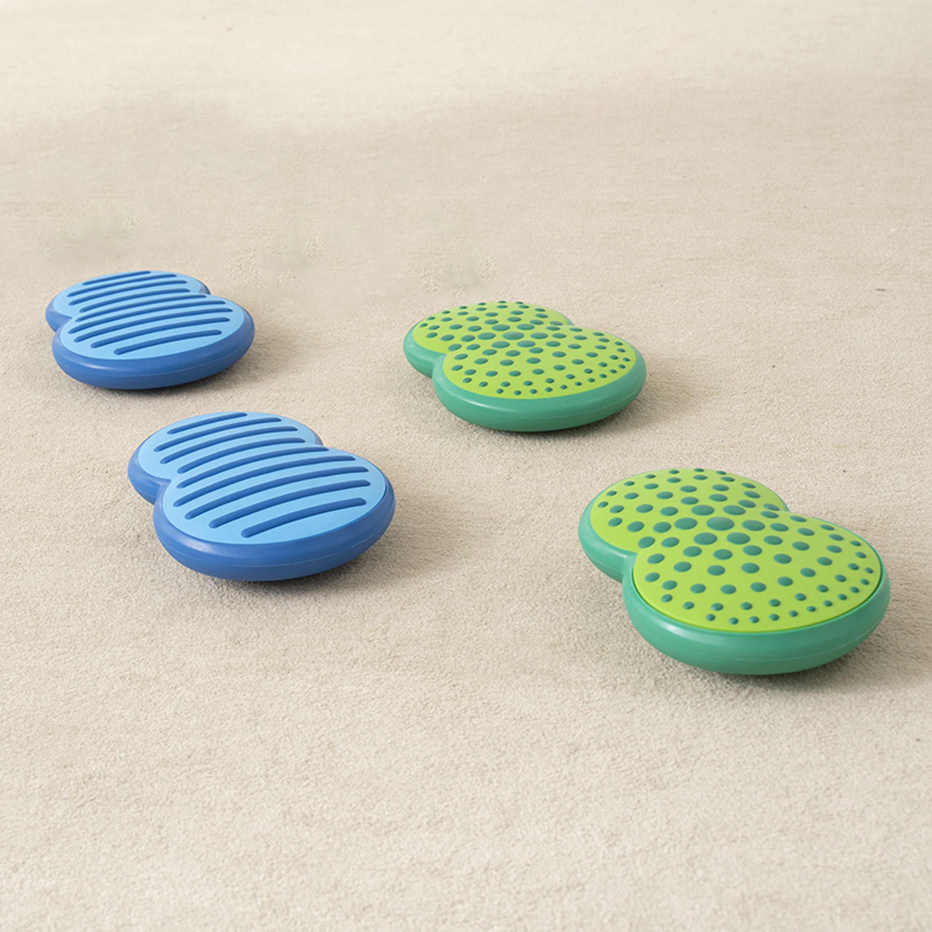 Two blue and two green stepping stones on a beige surface