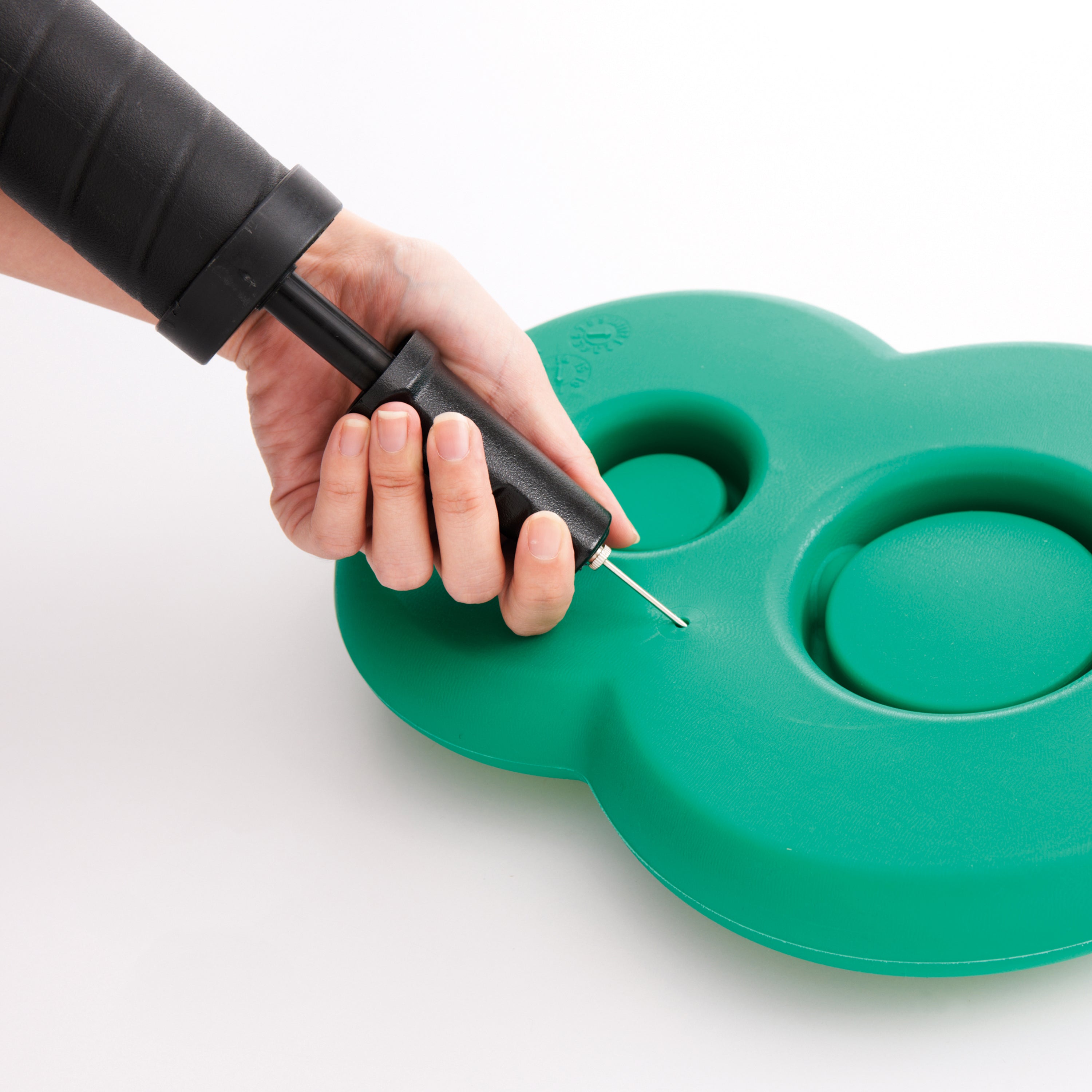 Hand using a black pump to inflate a green cloud-shaped object on a white background