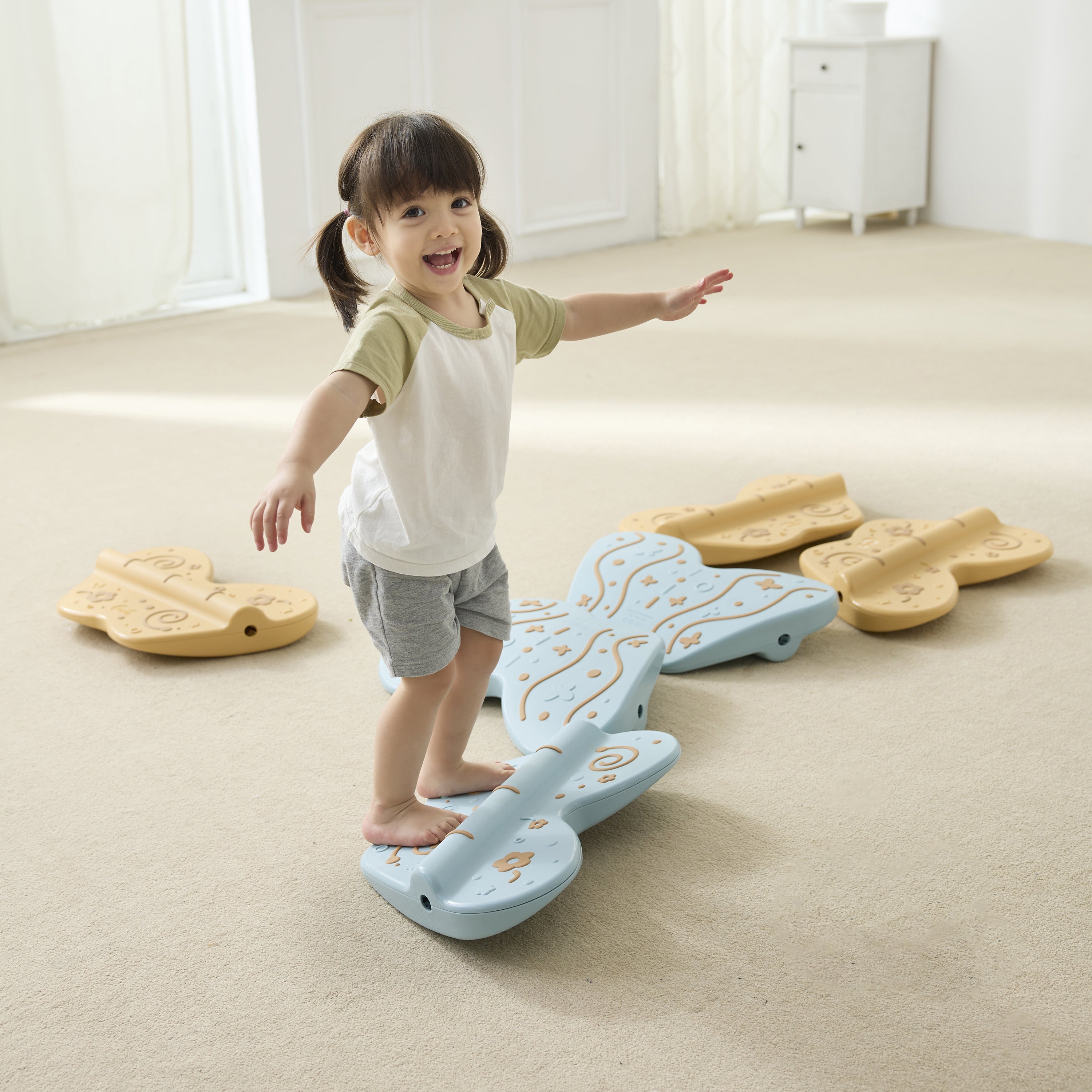 Child standing on a balance board in a room with light-colored flooring