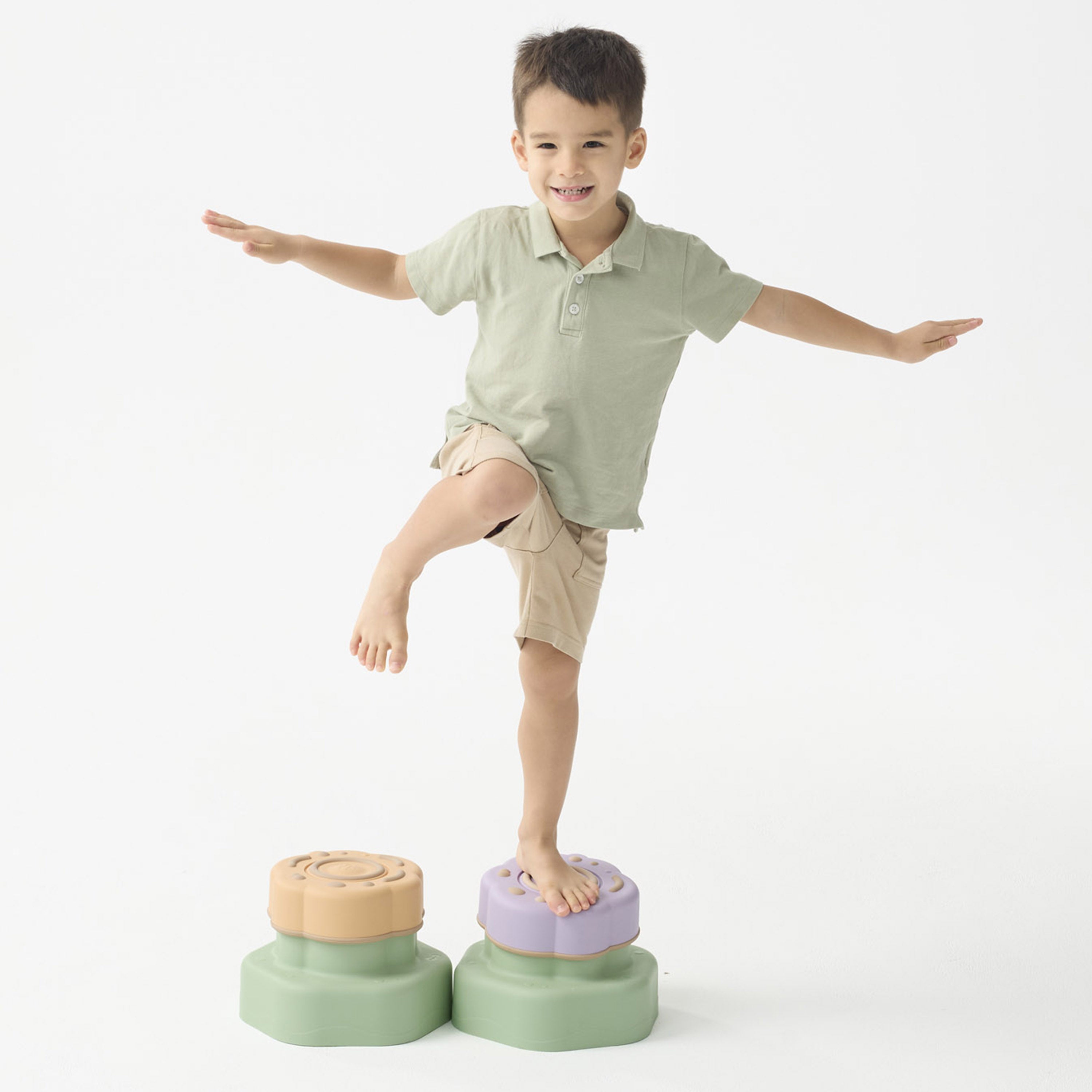 Child balancing on colorful stepping stones against a white background