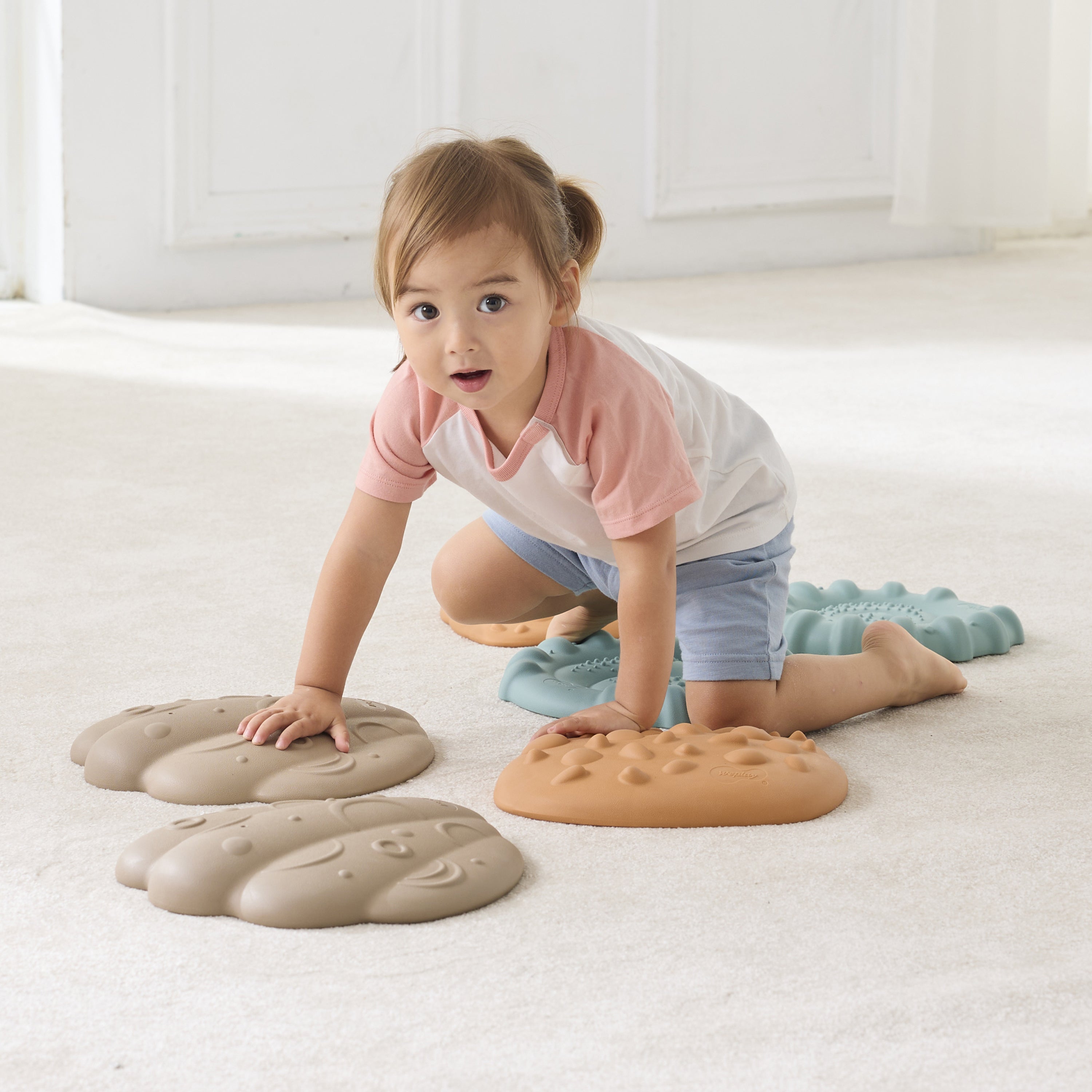 Child playing with textured steps on a light-colored floor.