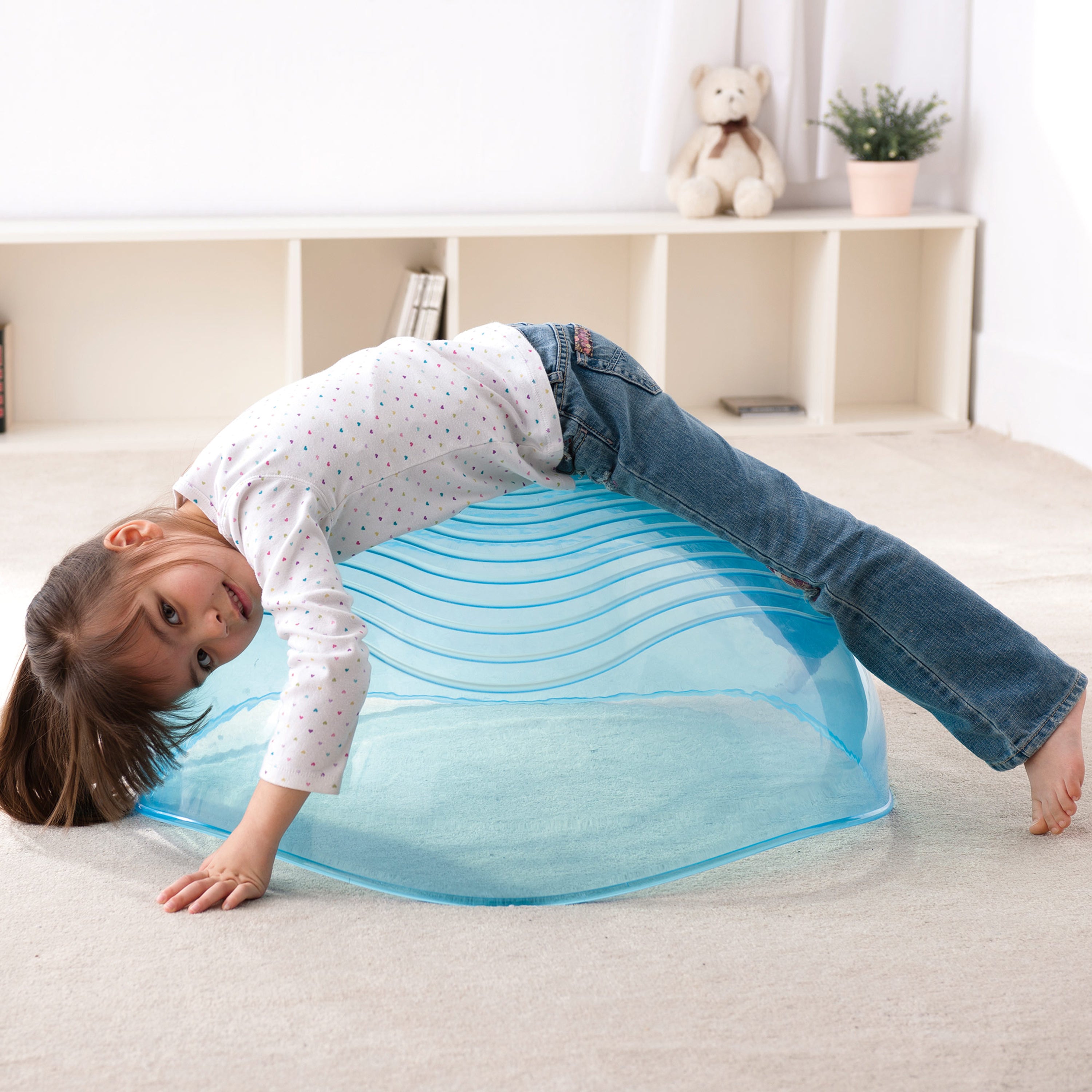 Child playing with a blue exercise ball on a carpeted floor.