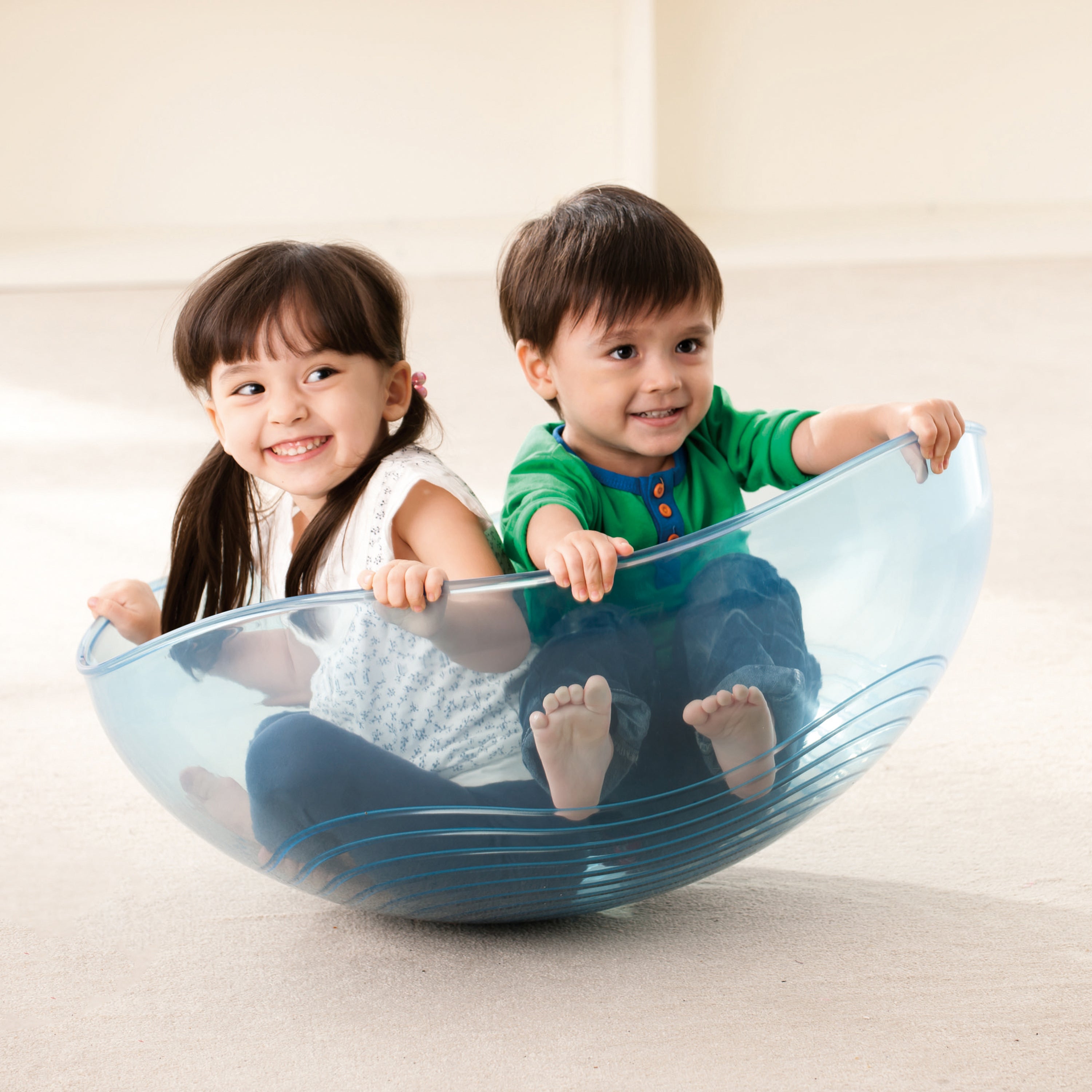 Two children playing inside a large blue ball on a light background