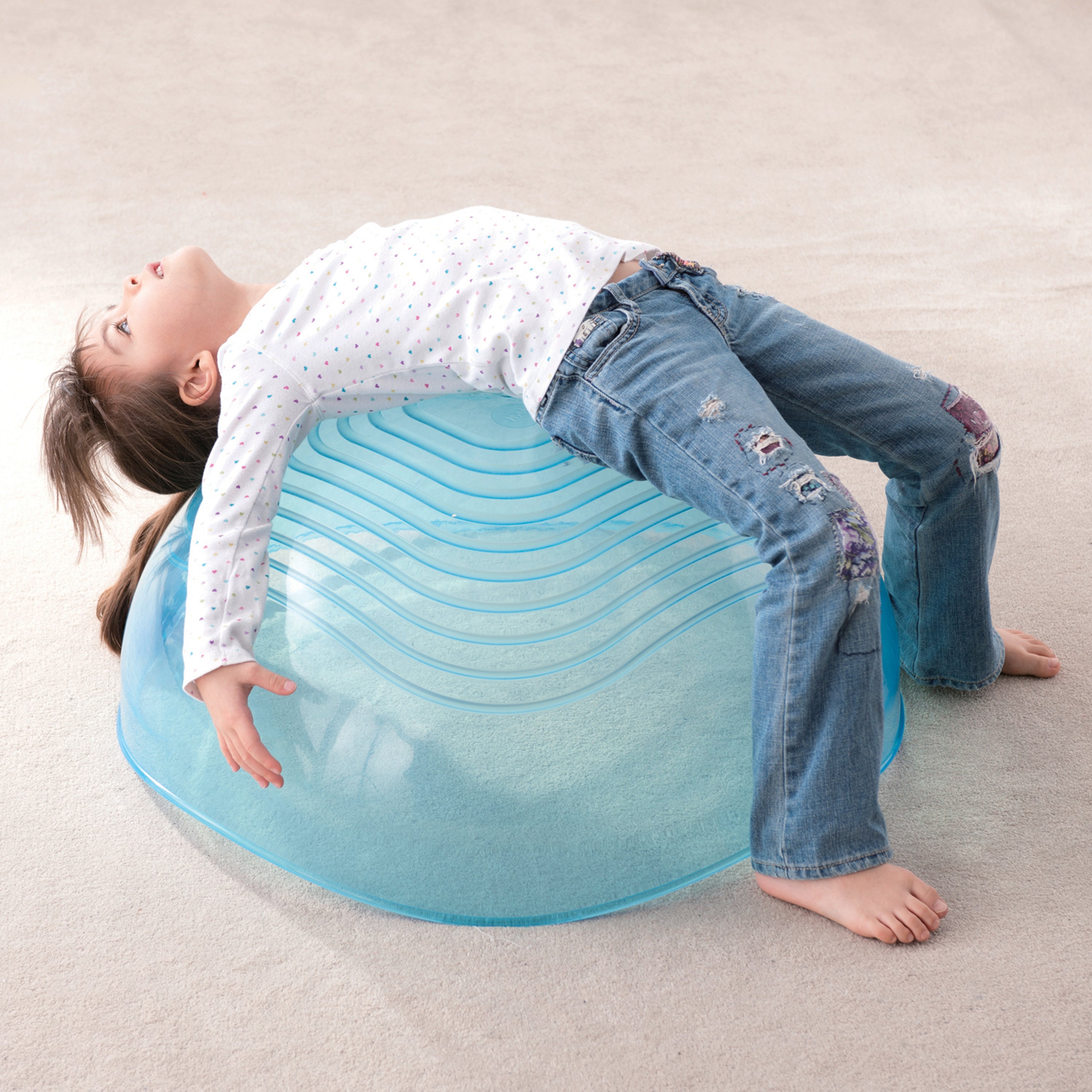 Child playing on a blue exercise ball on a carpeted floor