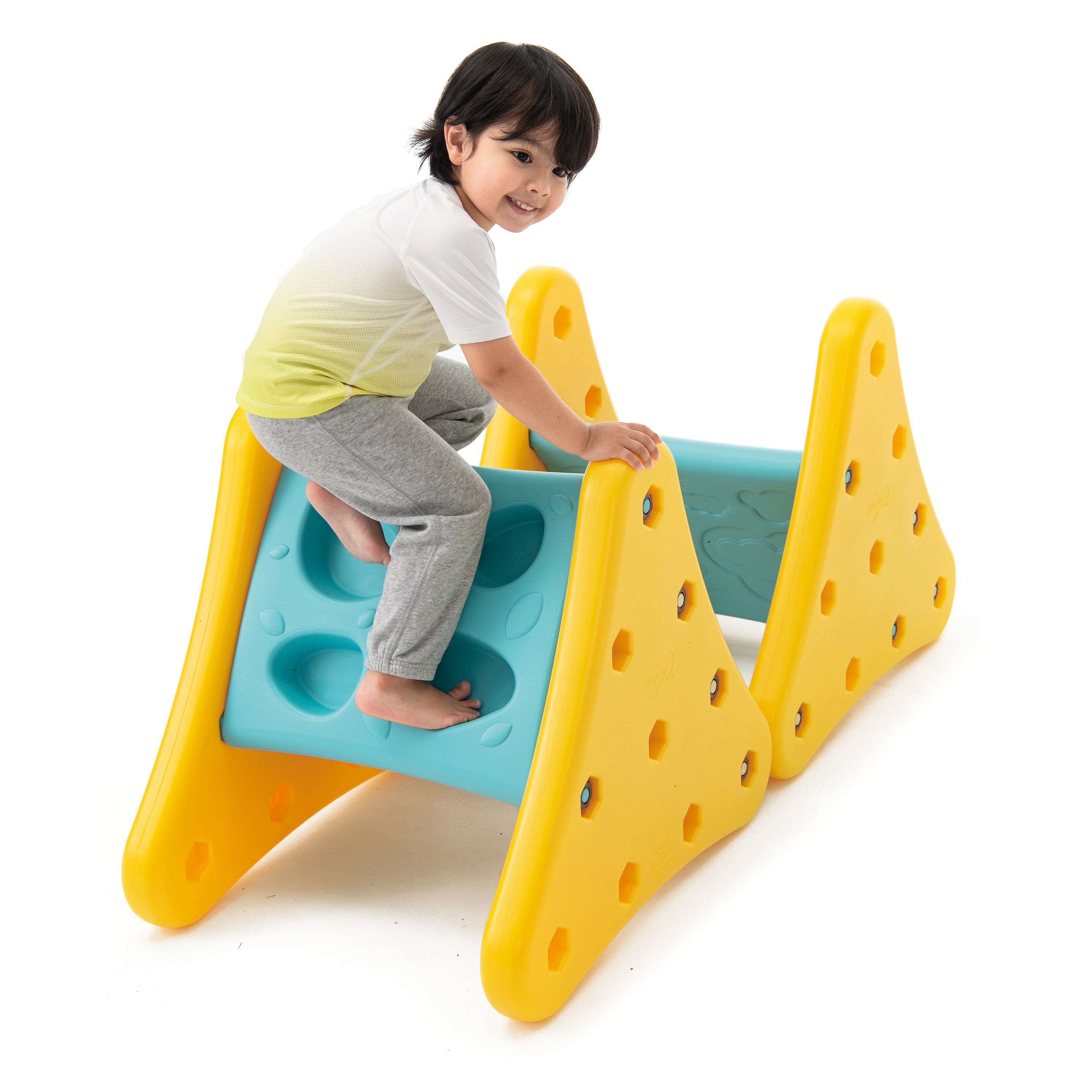 Child playing on a yellow and blue playground structure with a white background