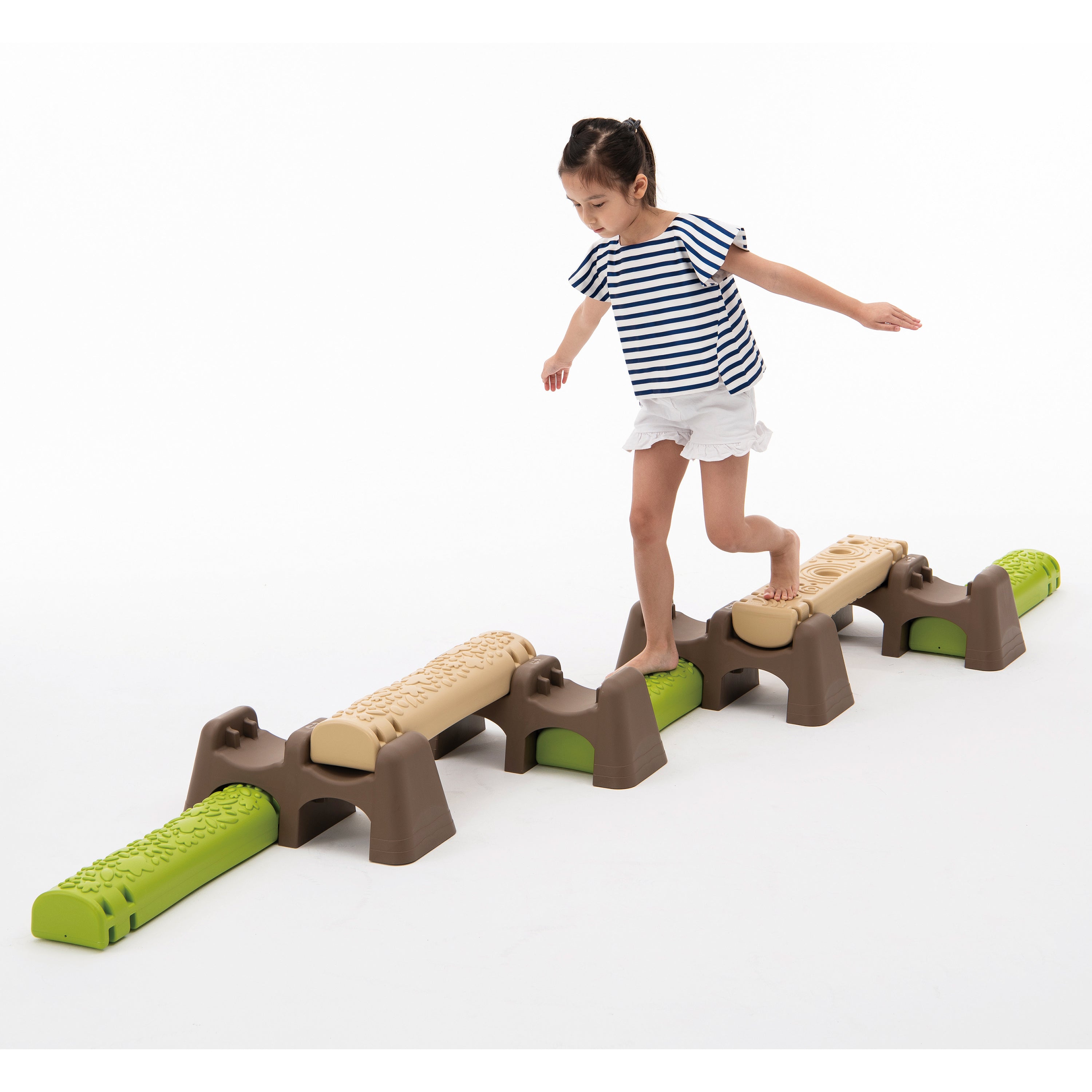 Child playing on a toy balance beam set with green and brown colors on a white background