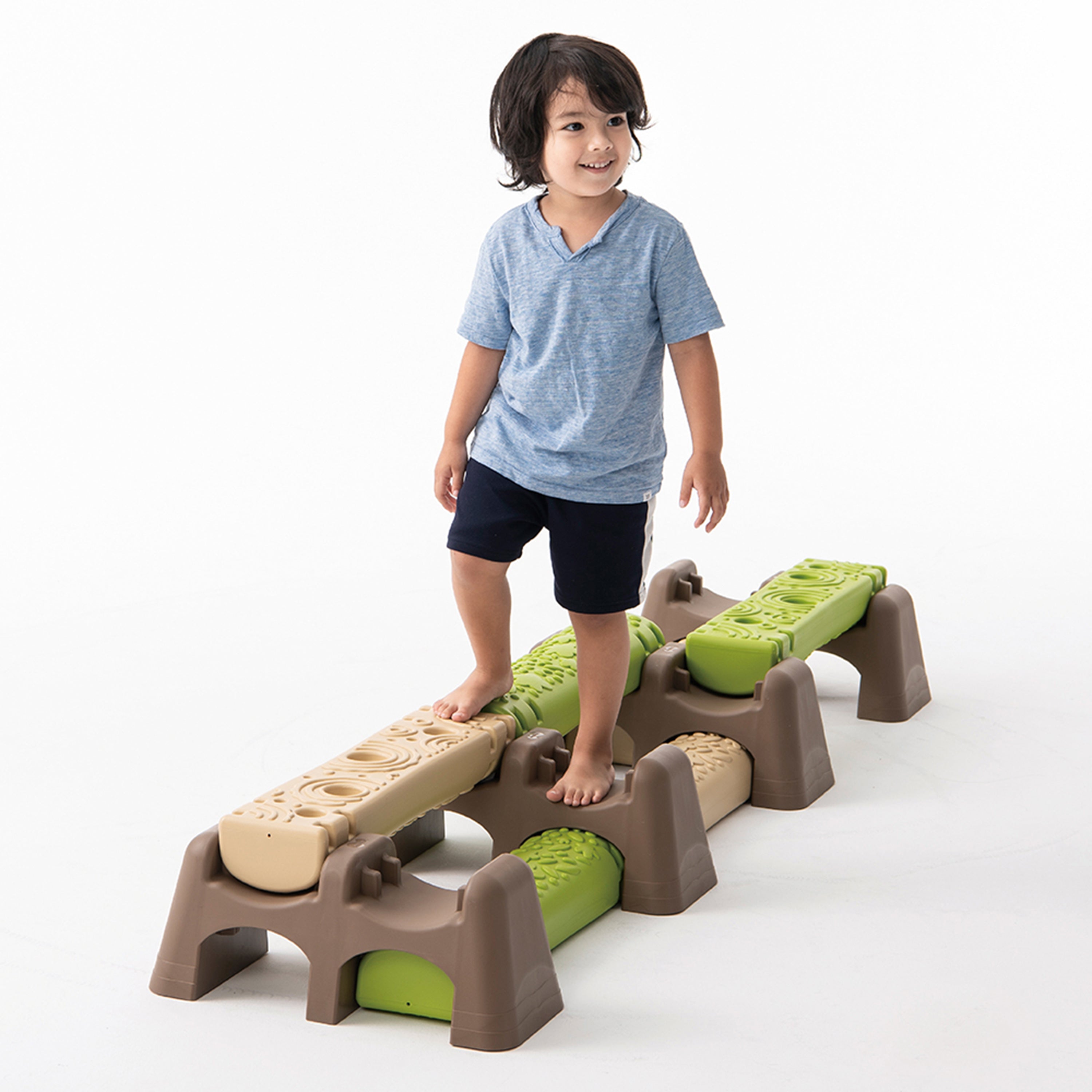 Child standing on a set of plastic stepping stones with a white background