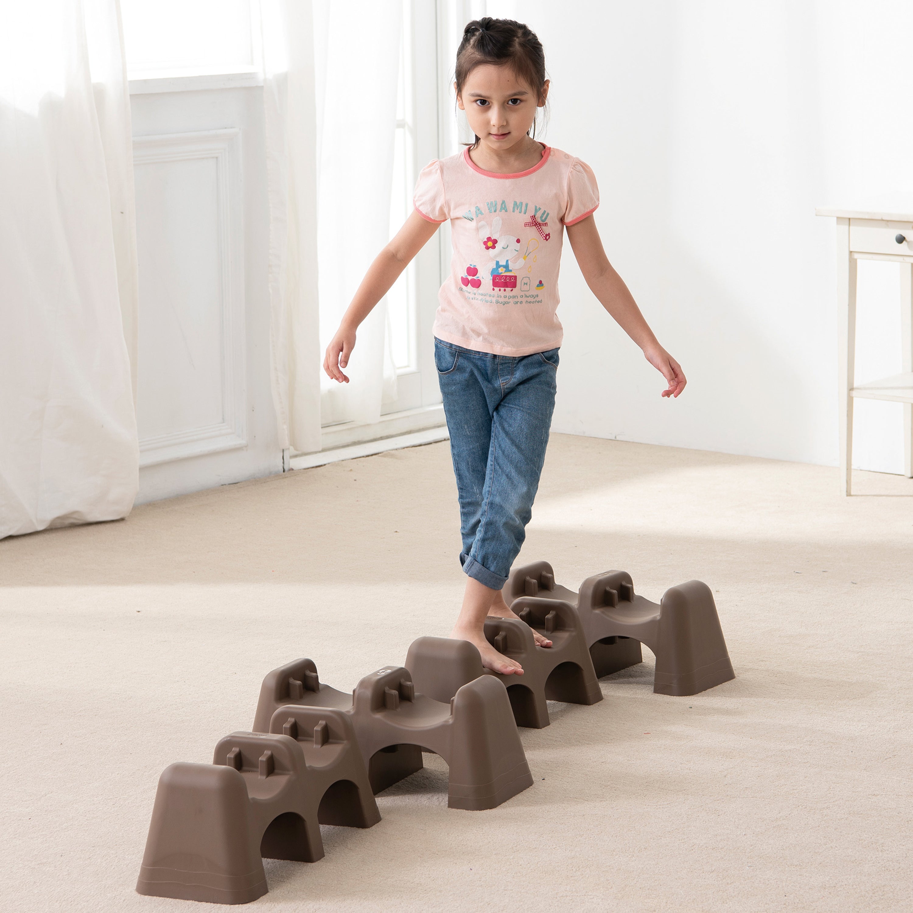 Child walking on a set of brown stepping stones indoors.