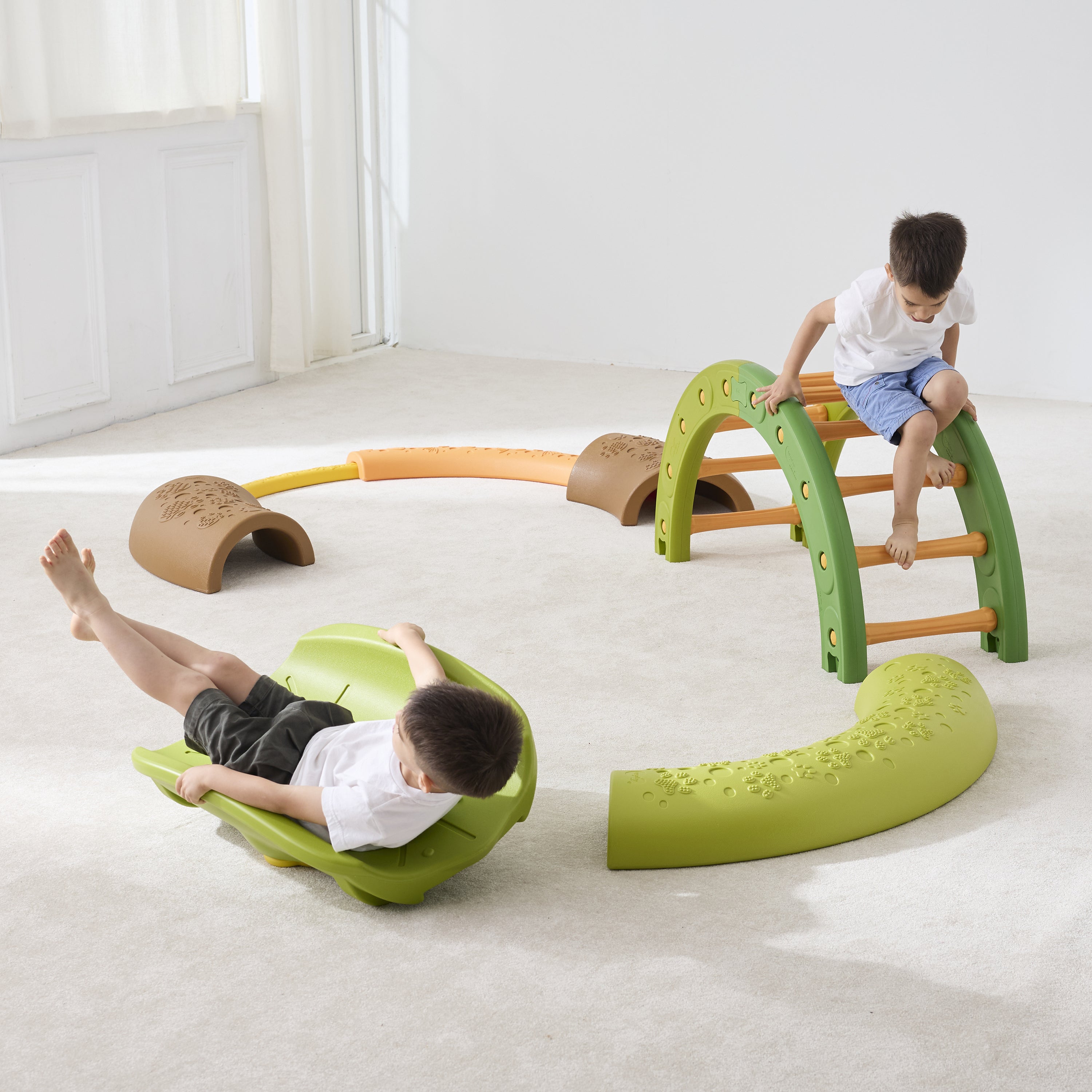 Children playing on a green and brown indoor play structure in a room with white walls and floor.