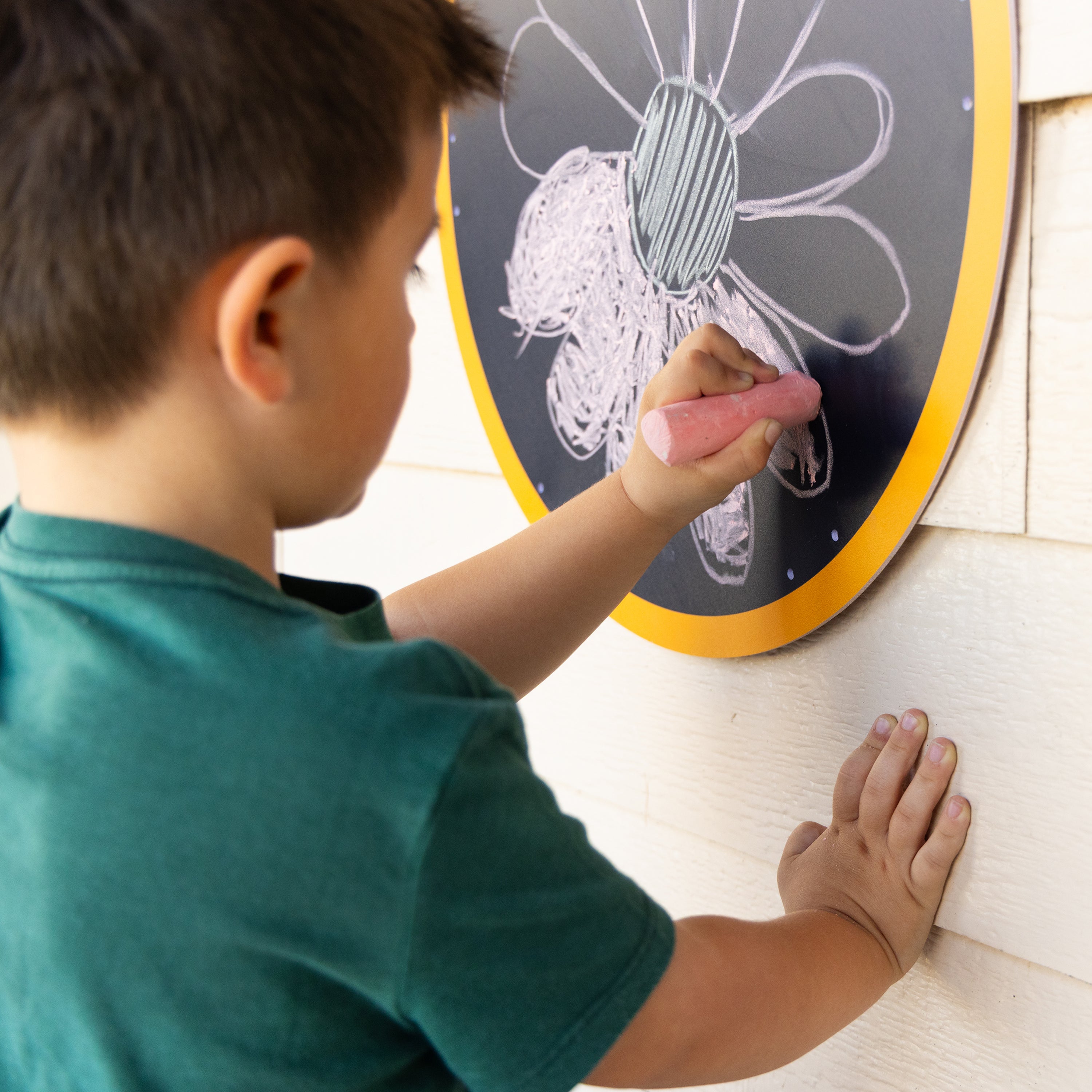 Child drawing on a round chalkboard with a pink eraser.