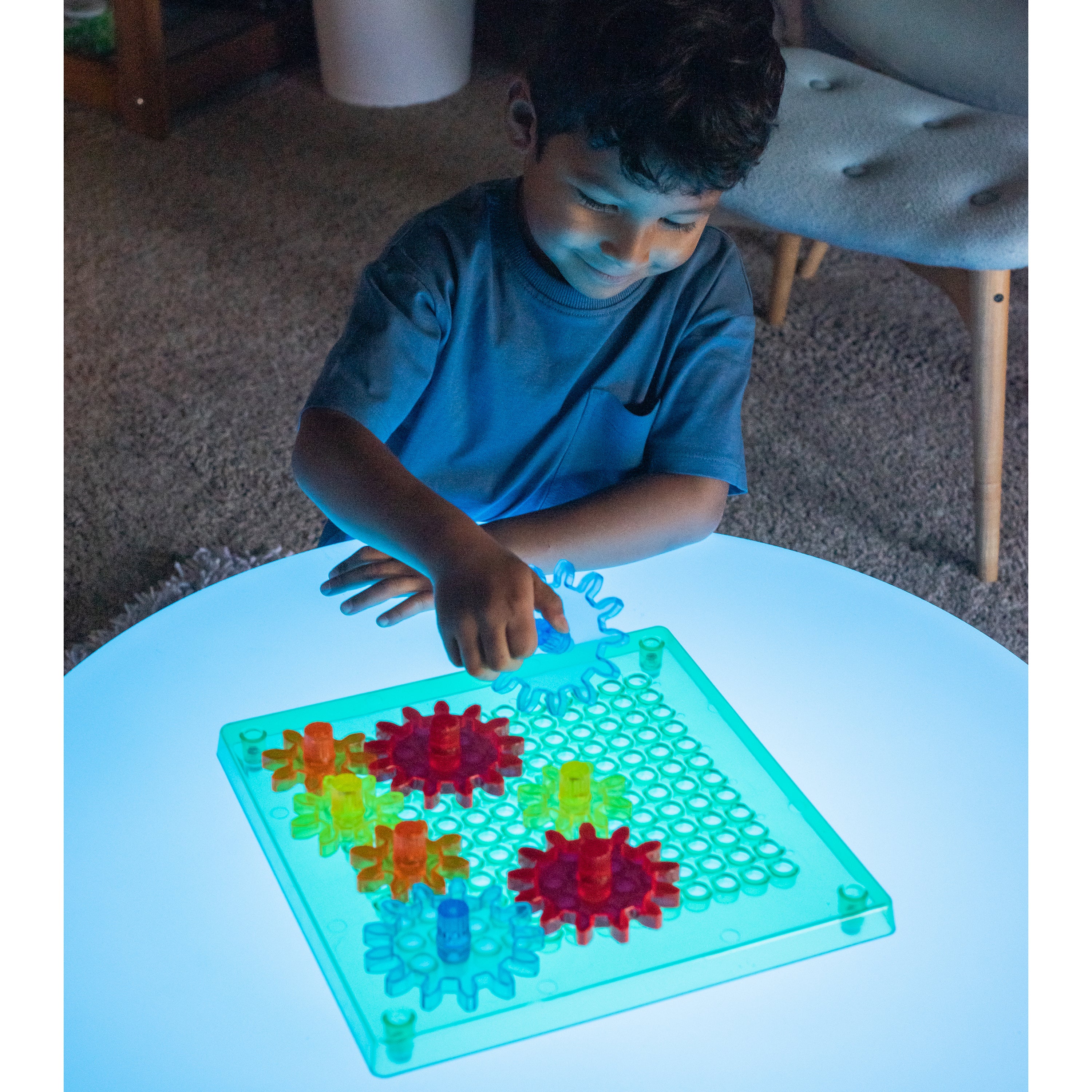 Child playing with a colorful puzzle on a glowing table