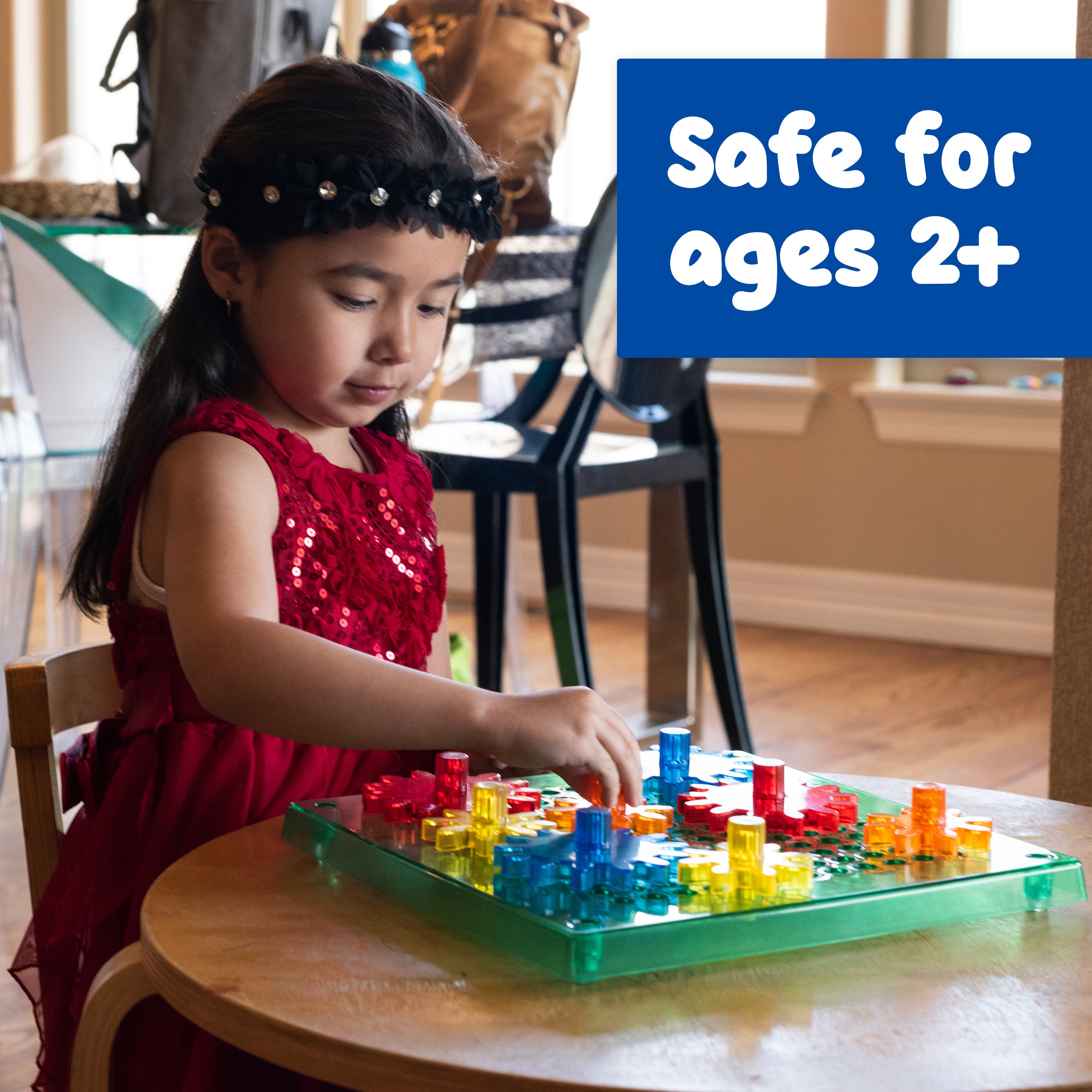 Child playing with colorful building blocks at a table, with text 'Safe for Ages 2+' in the corner.