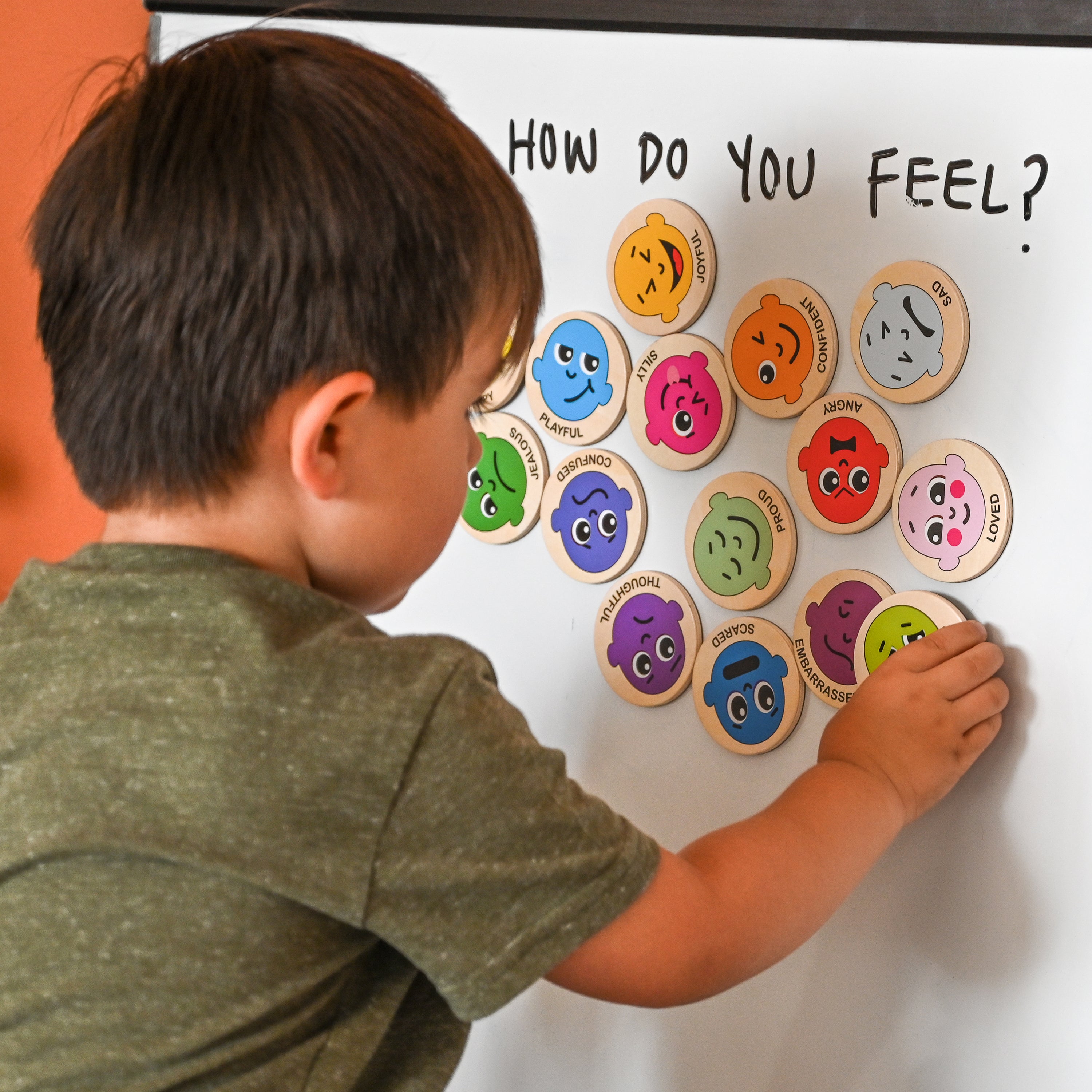 Child playing with emotion-themed magnets on whiteboard