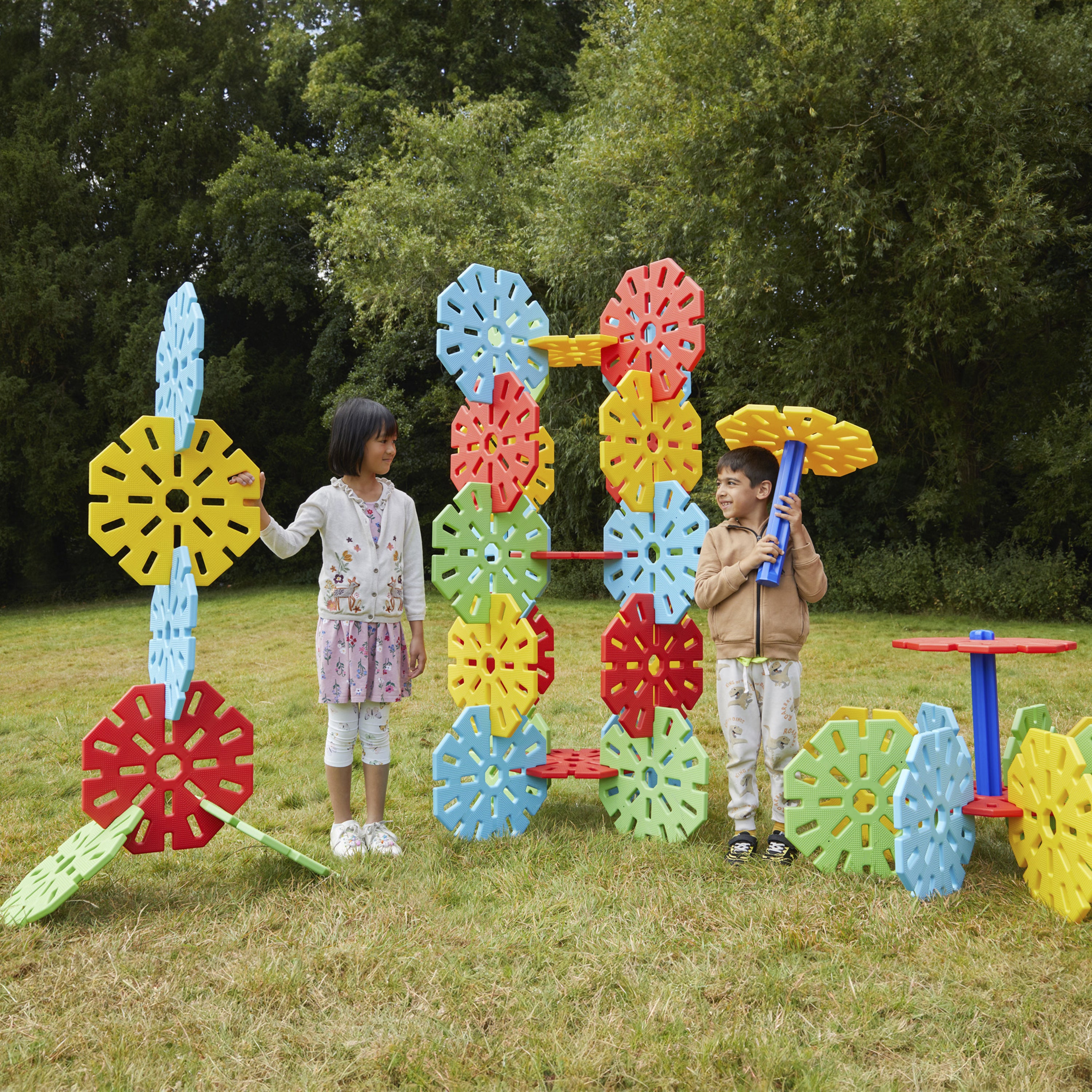 Two children playing with a colorful outdoor toy structure in a park.