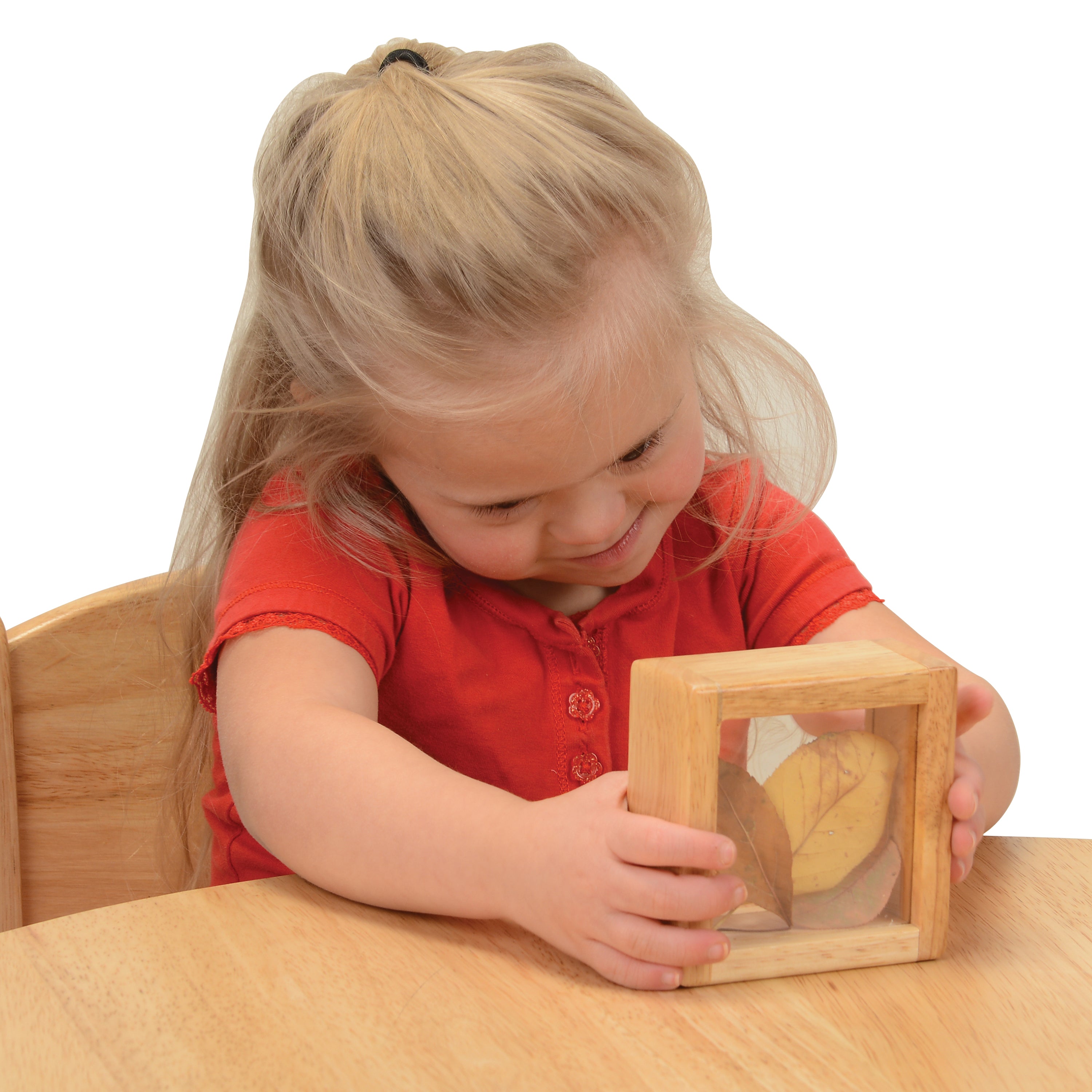 Child playing with a wooden leaf puzzle at a table.