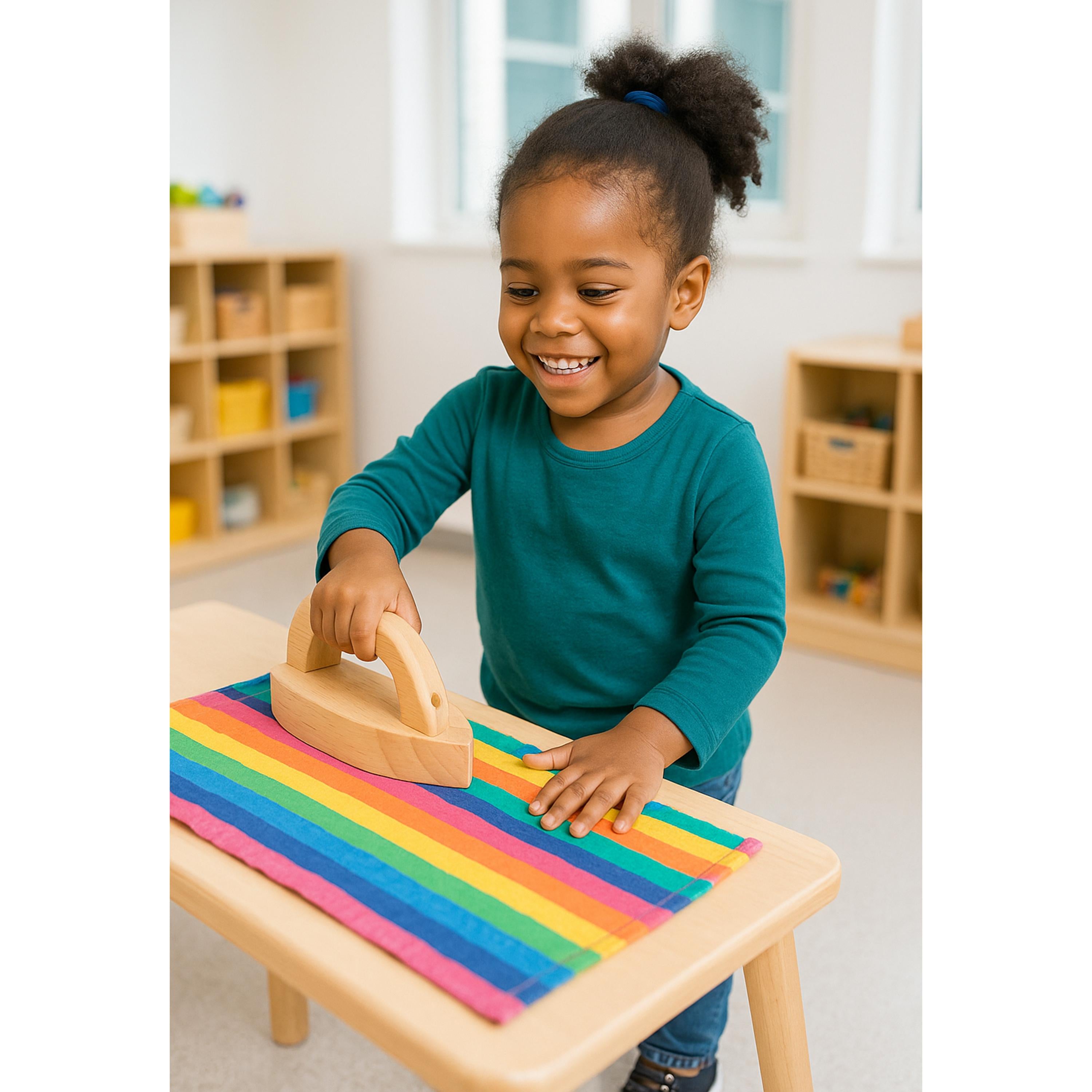 Child playing with a wooden toy iron in a classroom setting