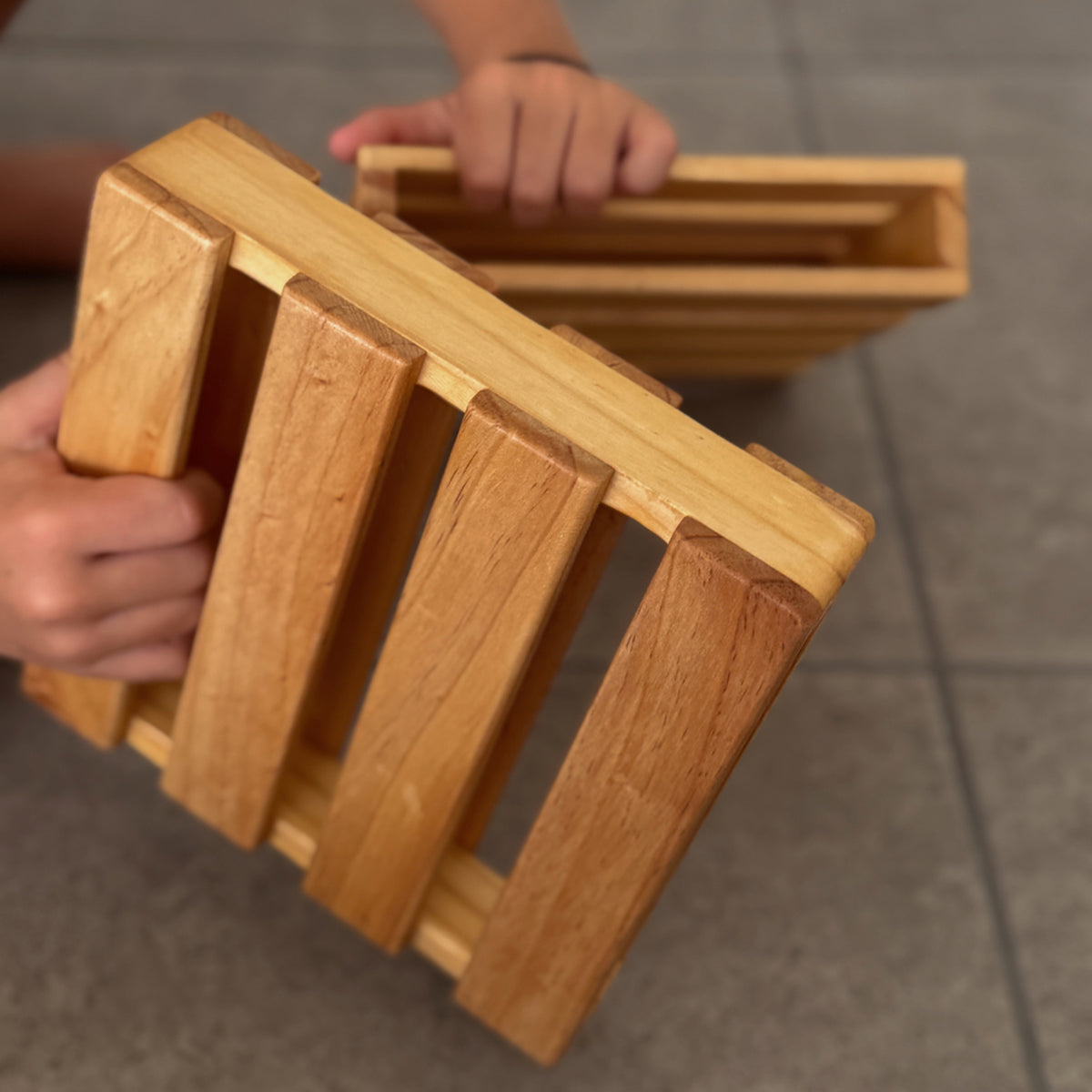 Child holding mini wooden pallets for screen-free building, stacking, and imaginative play