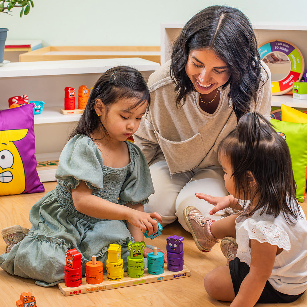 Woman and two young girls playing with colorful toys on the floor