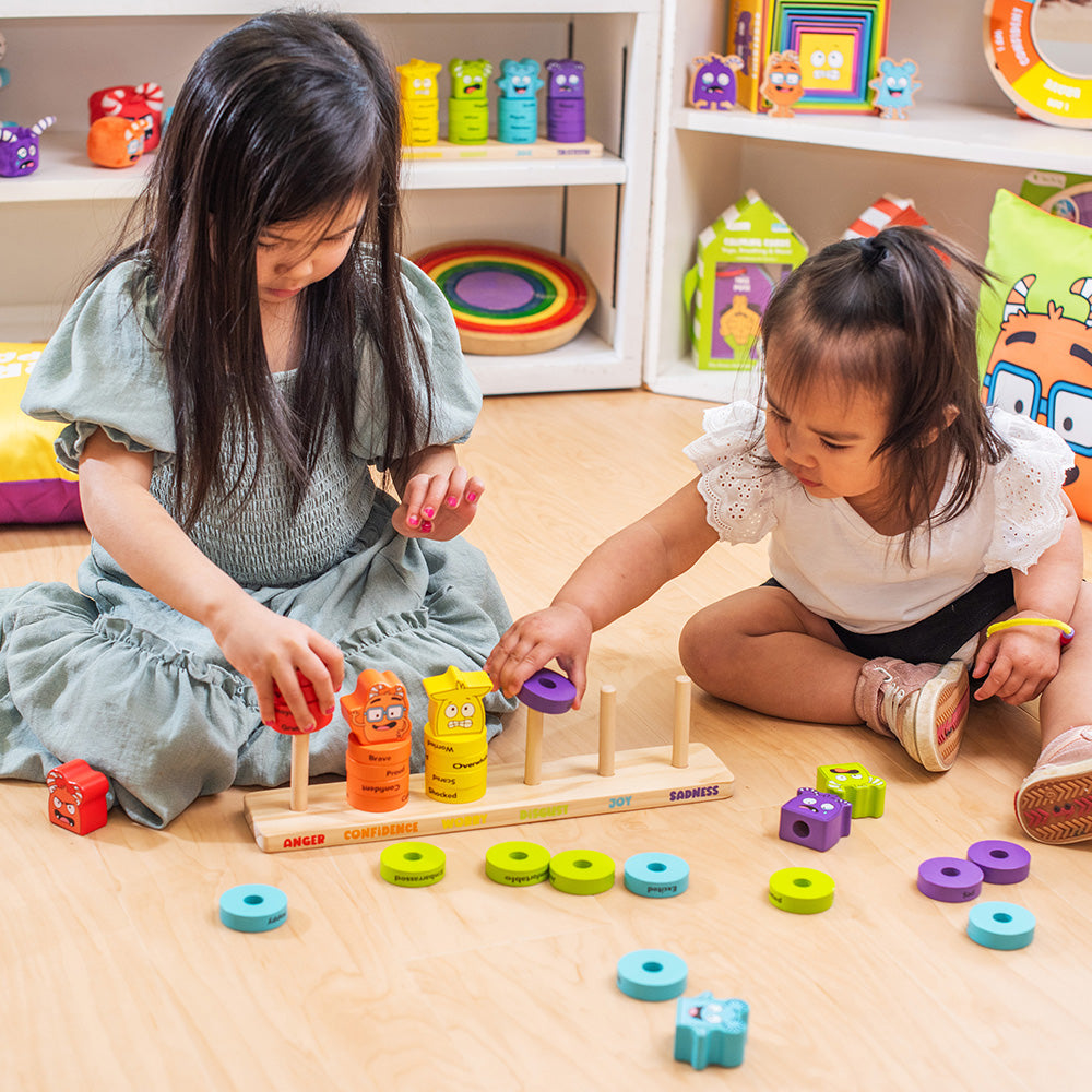 Two young children playing with colorful educational toys on a wooden floor.
