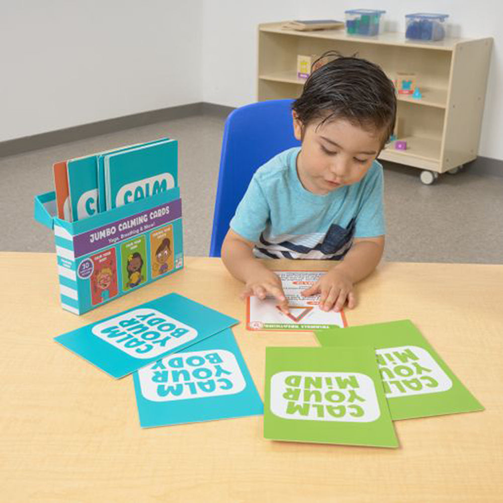 Child playing with educational cards on a table in a classroom setting